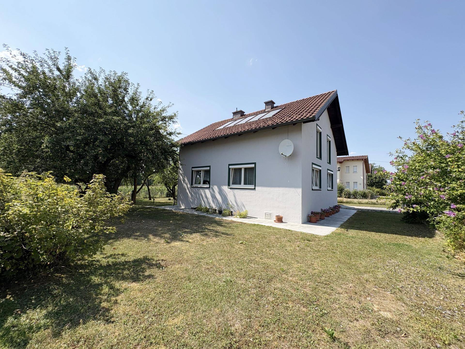 Seitenansicht des Hauses mit Satteldach, Dachfenstern und gepflegtem Gartenbereich.