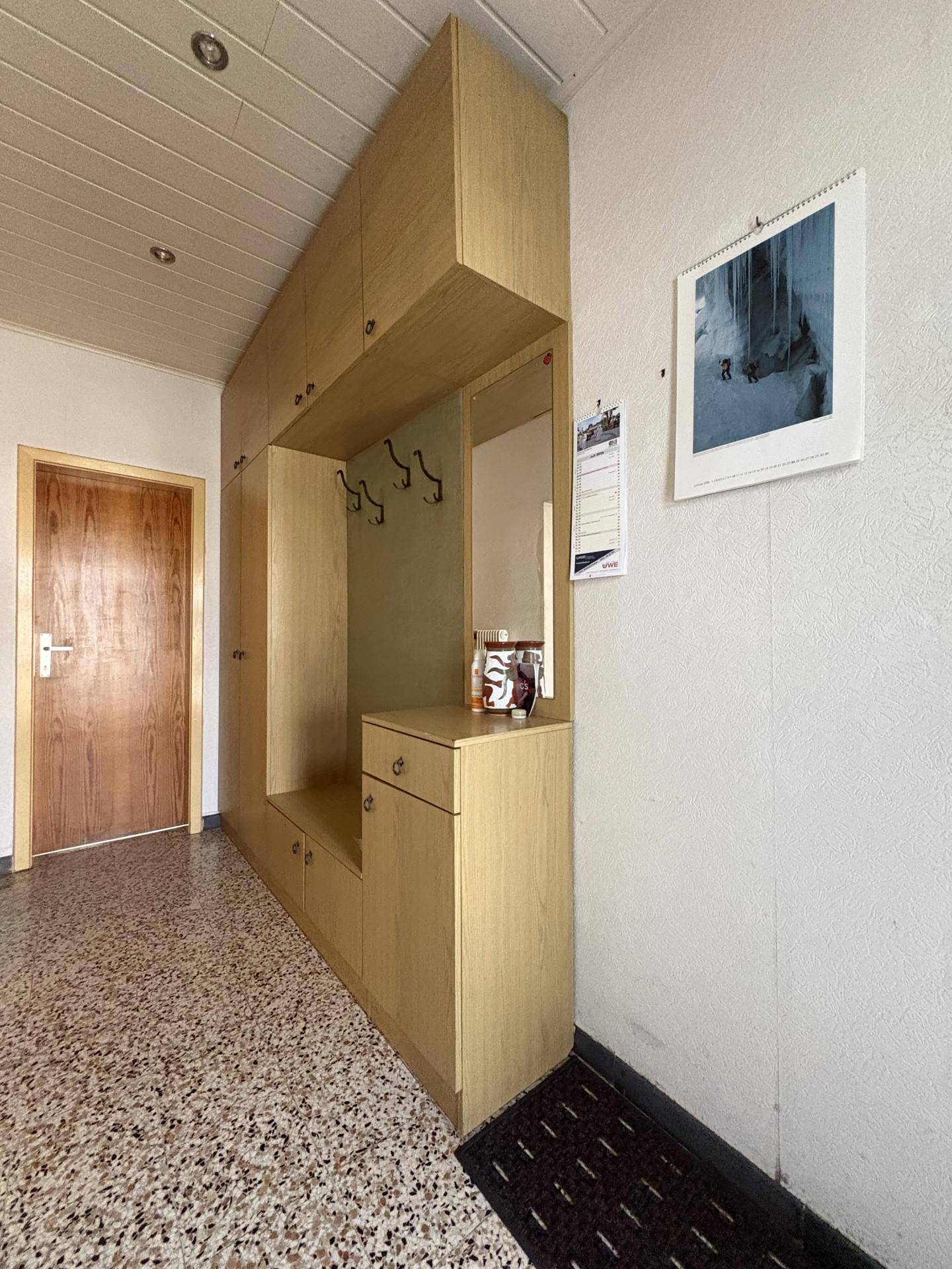 Eingangsbereich mit Einbauschrank, Garderobe, Spiegel und Terrazzoboden.