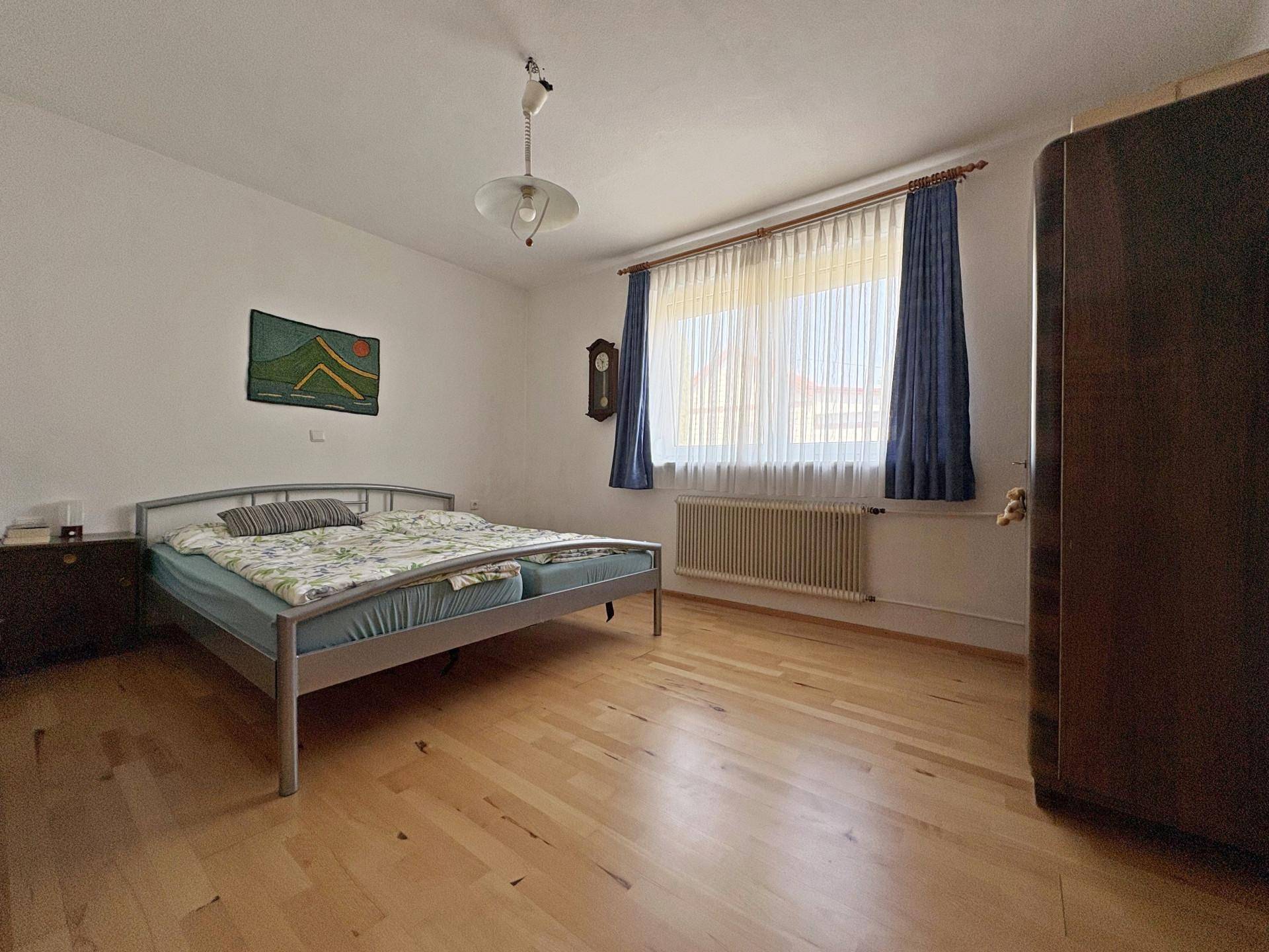 Schlafzimmer mit Holzboden, Doppelbett und großem Fenster mit Blick nach draußen.