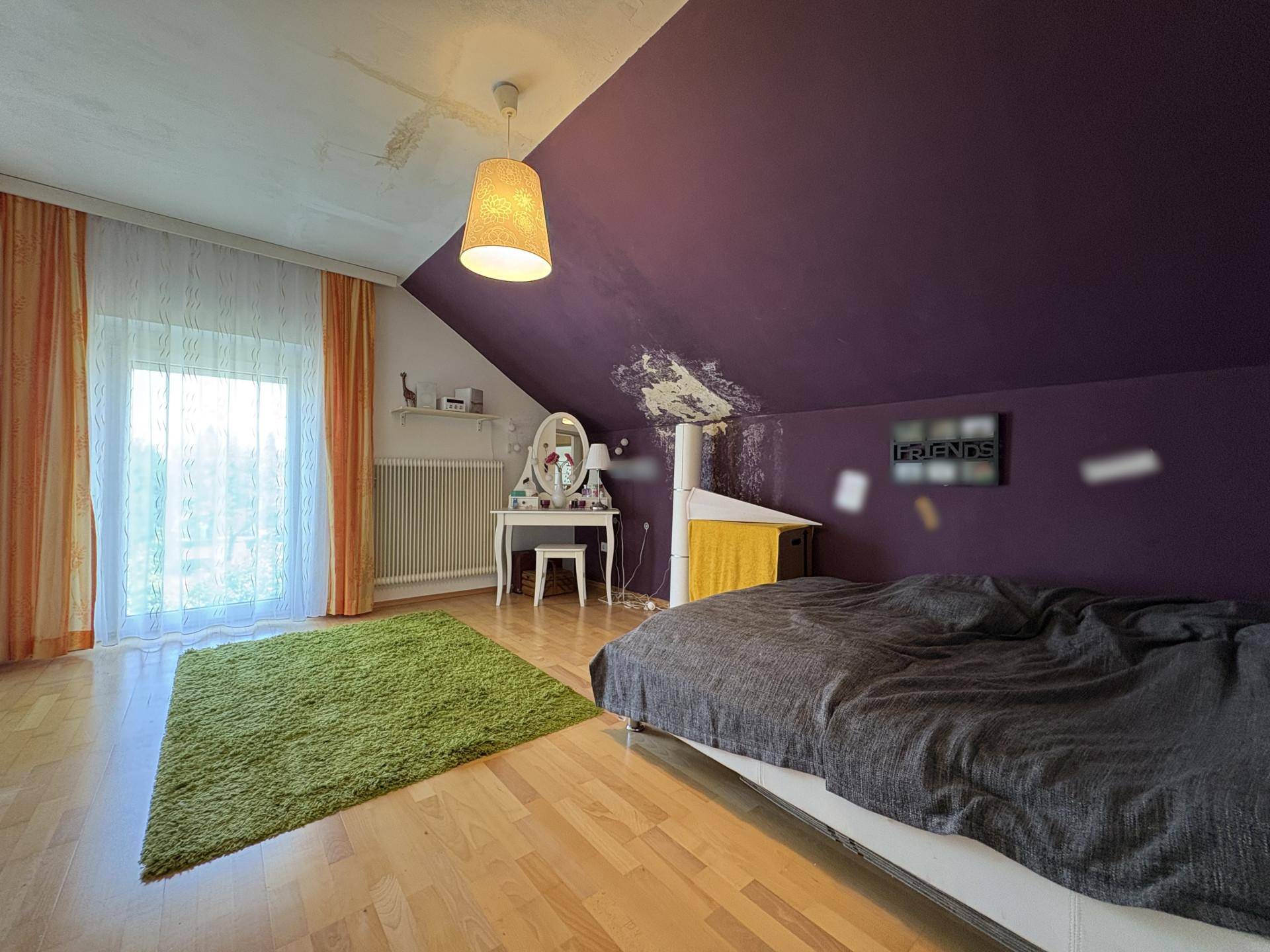 Farbenfrohes Schlafzimmer im Dachgeschoss mit lila Wand, Holzboden und Schminktisch.