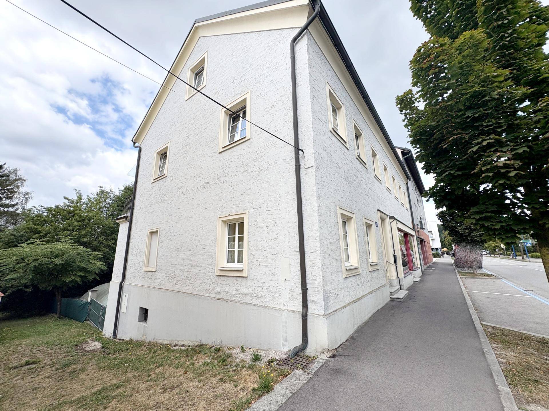 Nahaufnahme der strukturierten hellen Fassade des Gebäudes, die die Seitenansicht und den Gehweg zeigt.