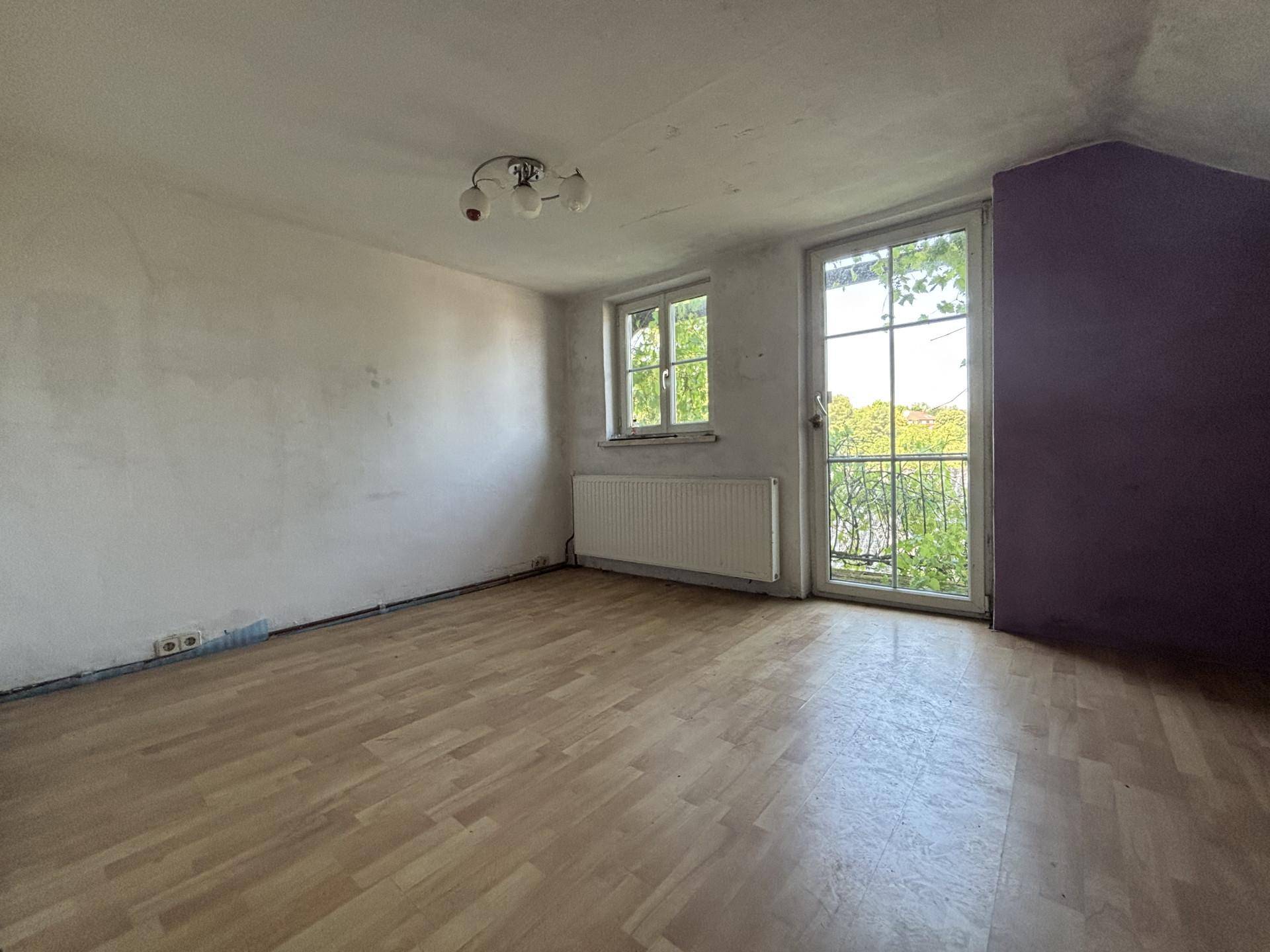 Heller Raum mit hellem Holzboden, weißen Wänden und Zugang zu einem Außenbereich.