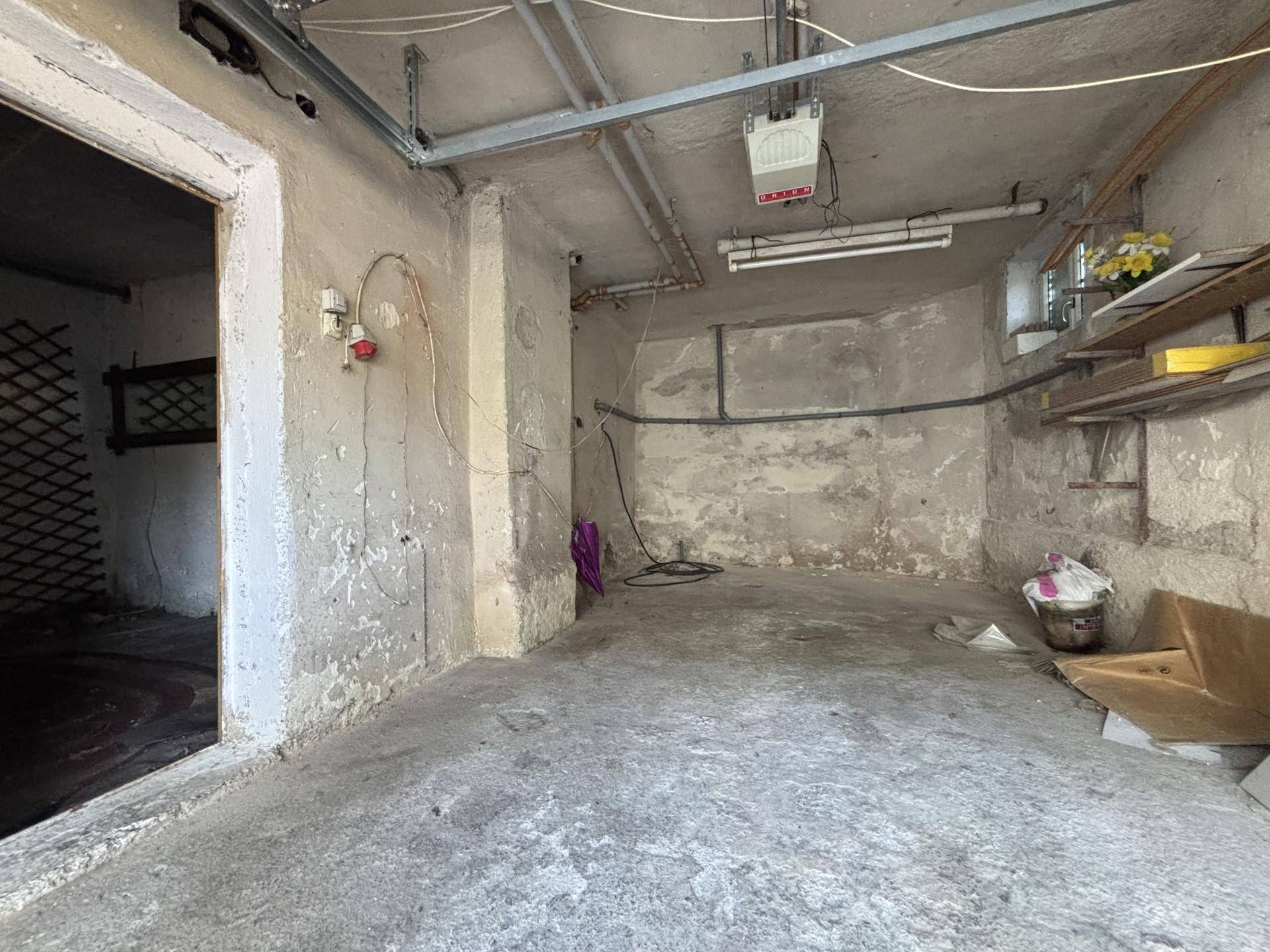 Innenansicht der Garage mit Betonboden und sichtbaren Installationen.