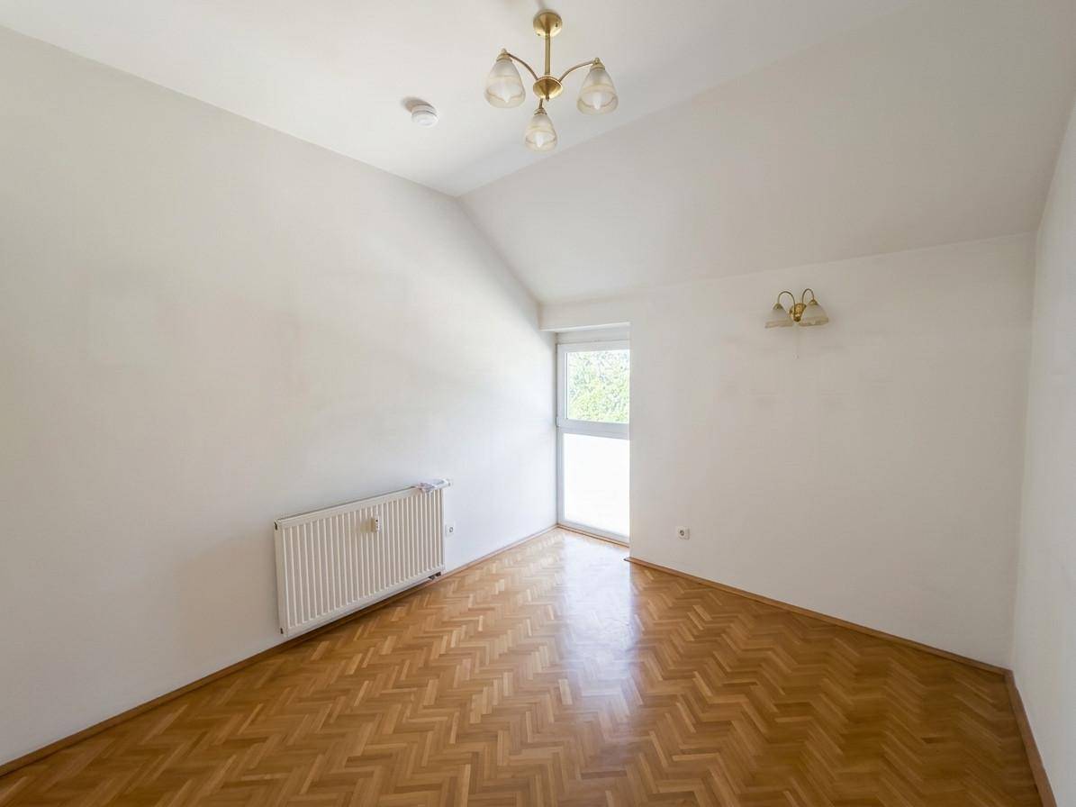 Helles, leeres Zimmer mit Fischgrätparkett, weiß gestrichenen Wänden und einem Fenster.