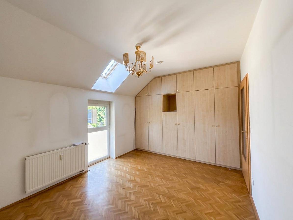 Schlafzimmer mit Einbauschränken, Fischgrätparkett, Dachfenster und viel natürlichem Licht.
