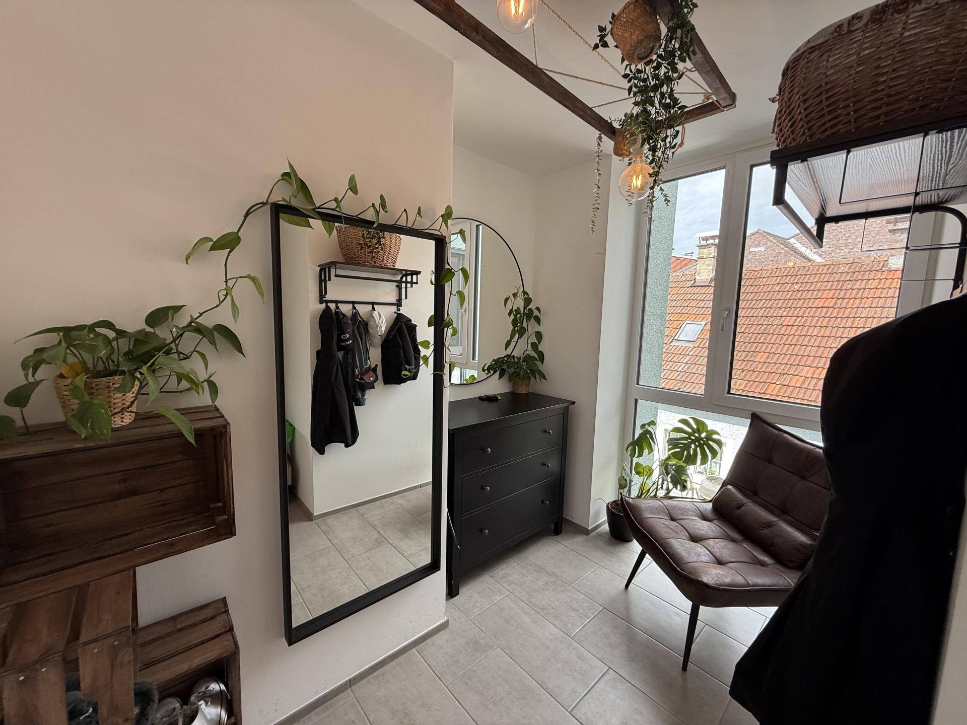 Heller Eingangsbereich mit großem Spiegel, Garderobe und Blick auf die Dächer.