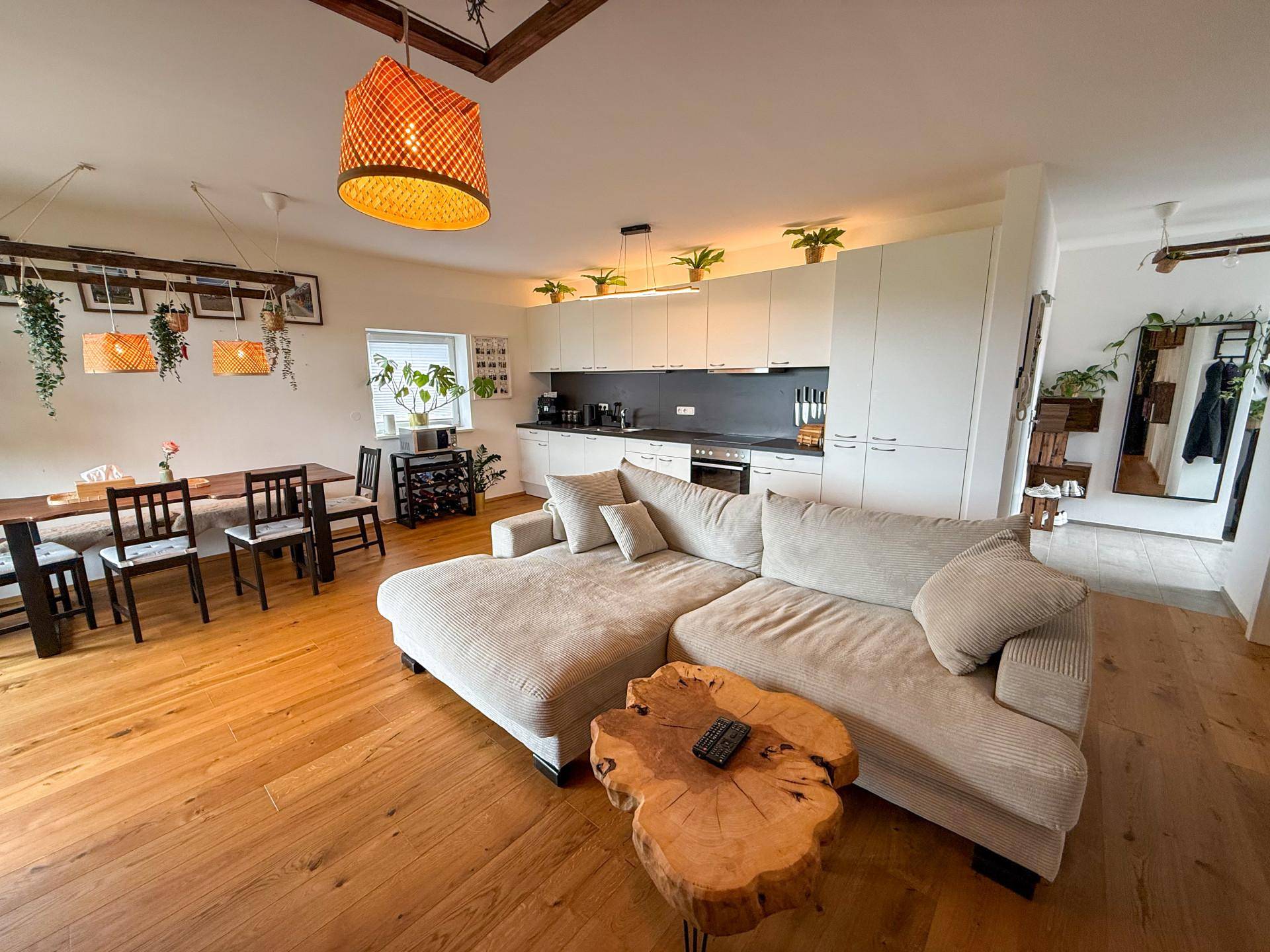 Geräumiger Wohnbereich mit beigem Ecksofa, Holzboden und moderner offener Küche.