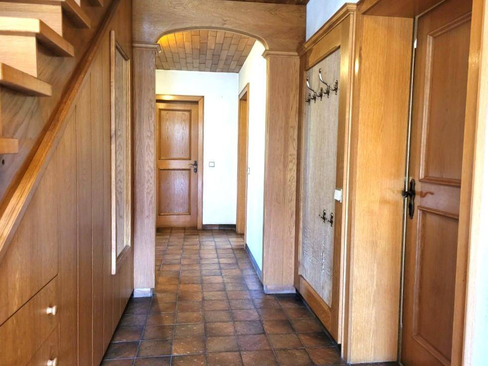 Flur mit Holztreppe, Terrakottafliesen und Holztüren im traditionellen Stil.