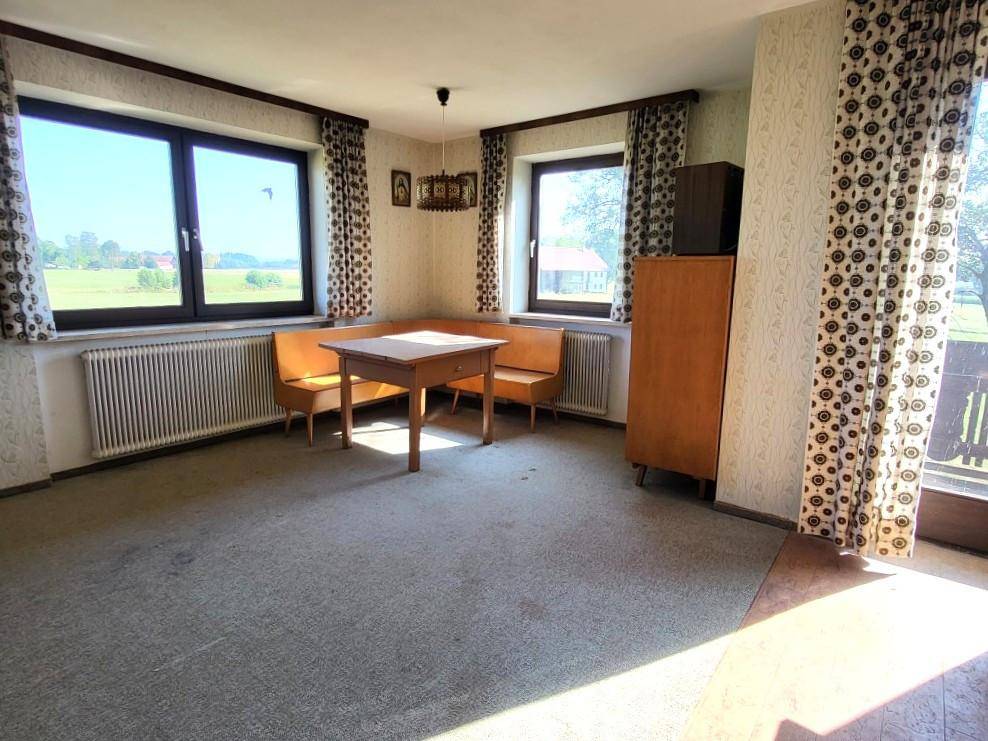Wohn-Essbereich mit Teppichboden, eingebauter Sitzbank und Zugang zum Balkon.