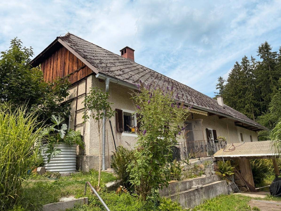Charmantes Landhaus mit Holzelementen und üppiger Vegetation in ländlicher Umgebung.