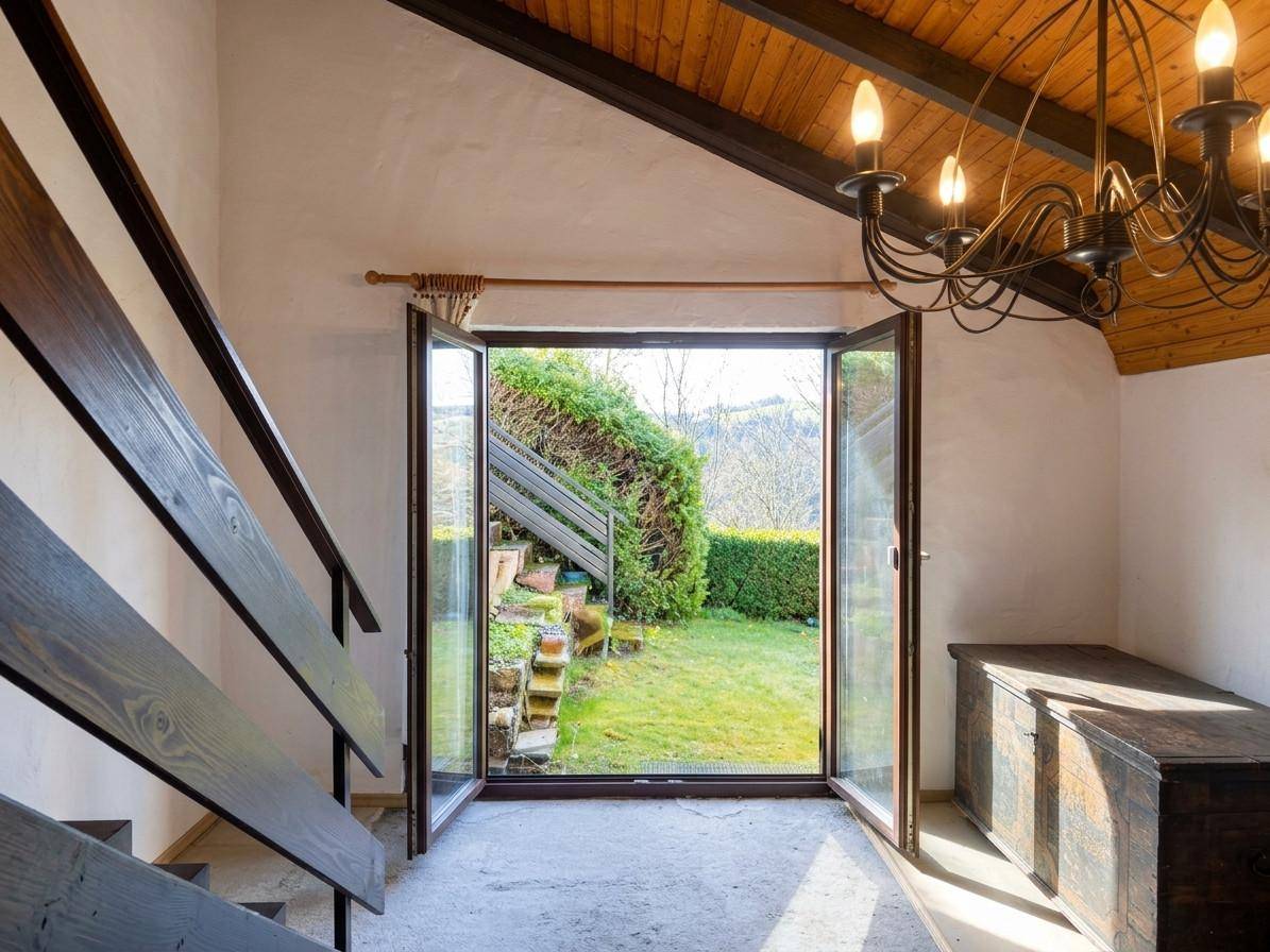 Heller Eingangsbereich mit Holztreppe und Glastür, die direkten Zugang zum Garten bietet.