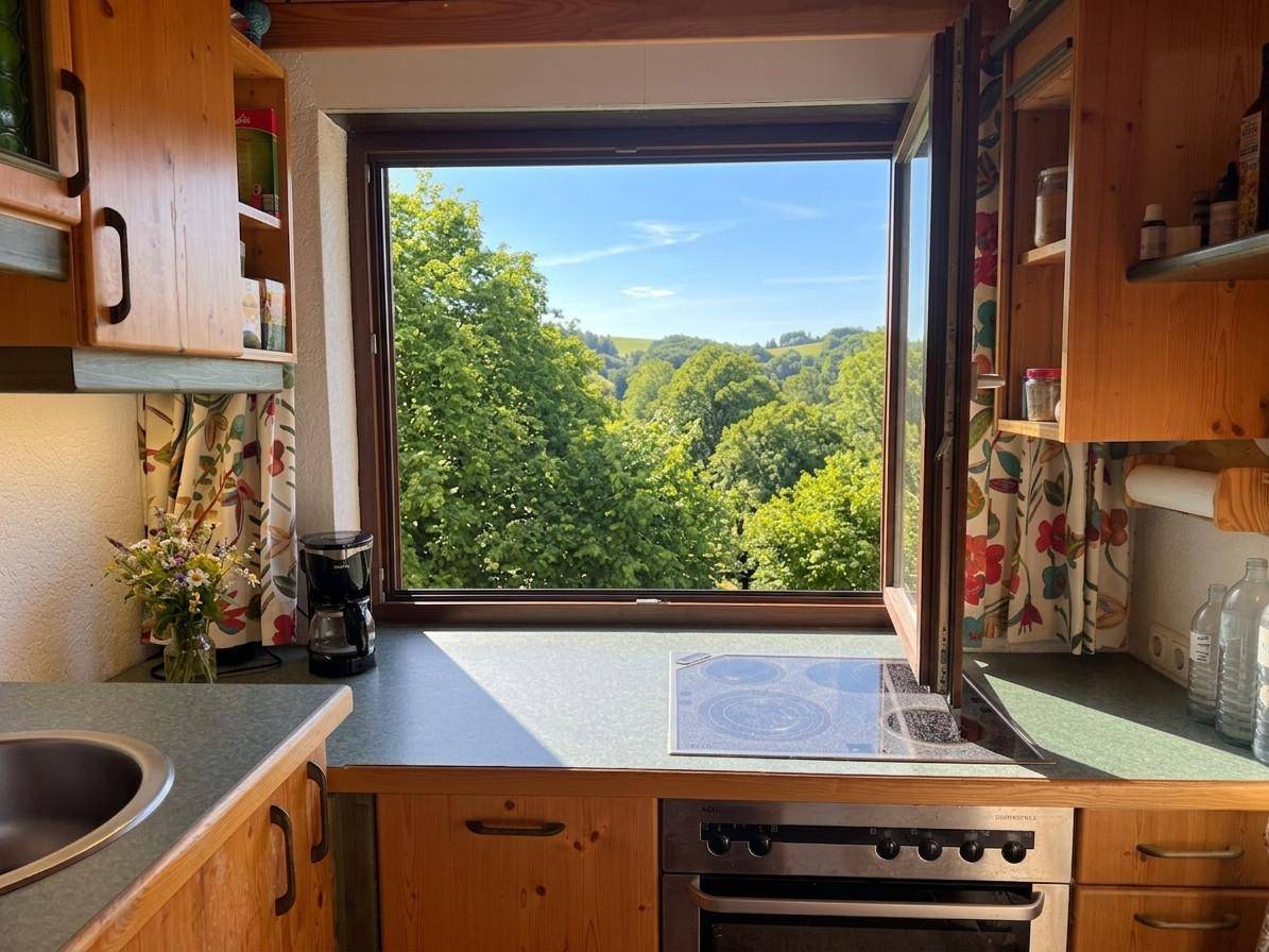 Kleine Holzküche mit Fenster und Kochfeld, bietet einen schönen Ausblick in die grüne Landschaft.