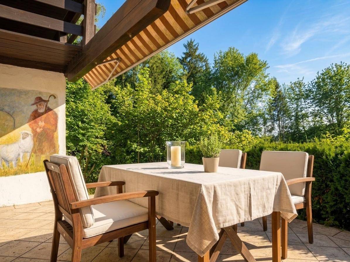 Gemütliche Terrasse mit Holztisch und Stühlen, ideal für Mahlzeiten im Freien mit Blick ins Grüne.