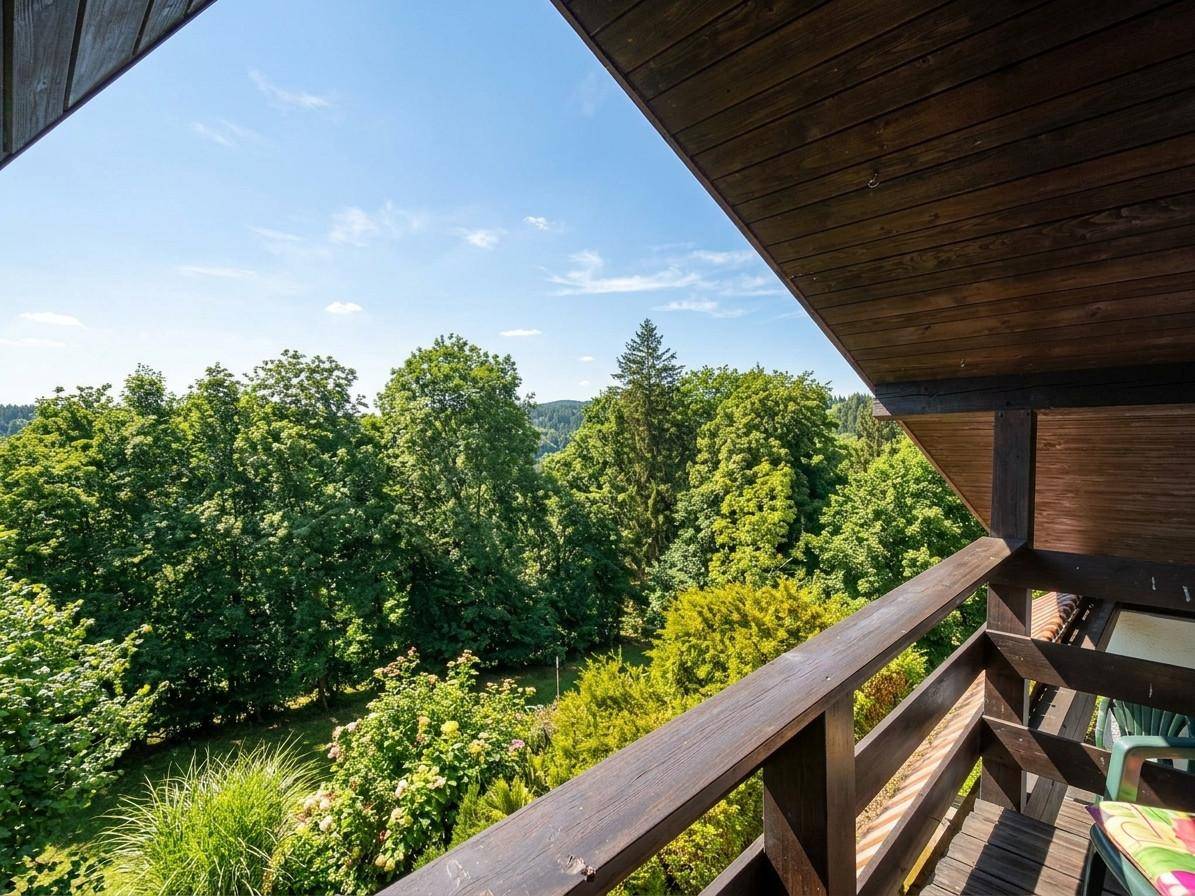 Holzbalkon mit weitem Blick über die grüne Hügellandschaft und dichte Wälder.