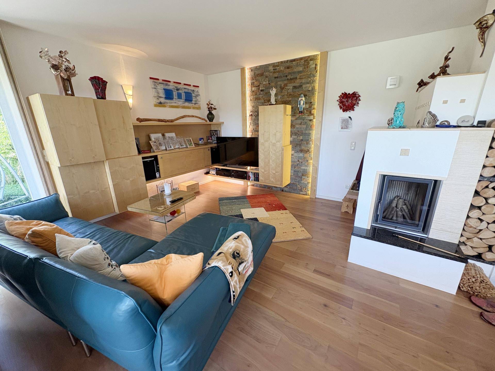 Gemütliches Wohnzimmer mit blauem Sofa, modernem Kamin und einer Akzentwand aus Naturstein.