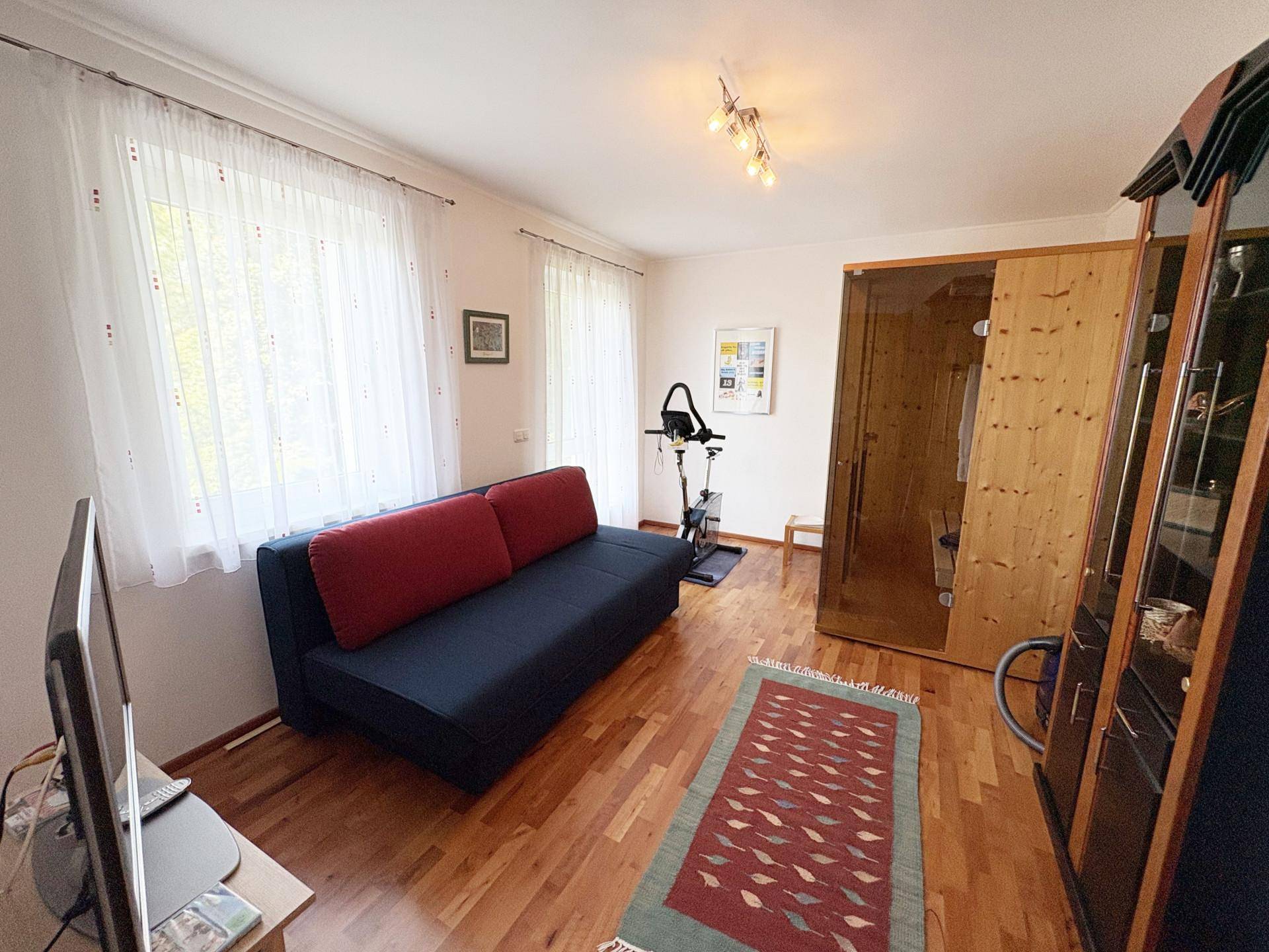 Raum mit Sofa, Heimtrainer und einer privaten Sauna, ideal für Entspannung und Fitness.