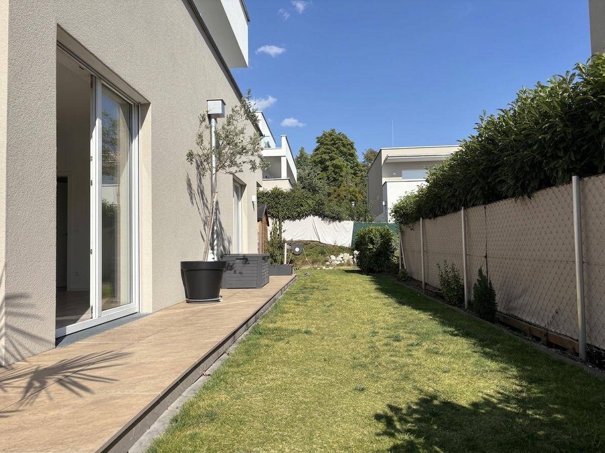 Langer, schmaler Gartenbereich entlang des Hauses mit hoher Hecke und gepflegtem Rasen.