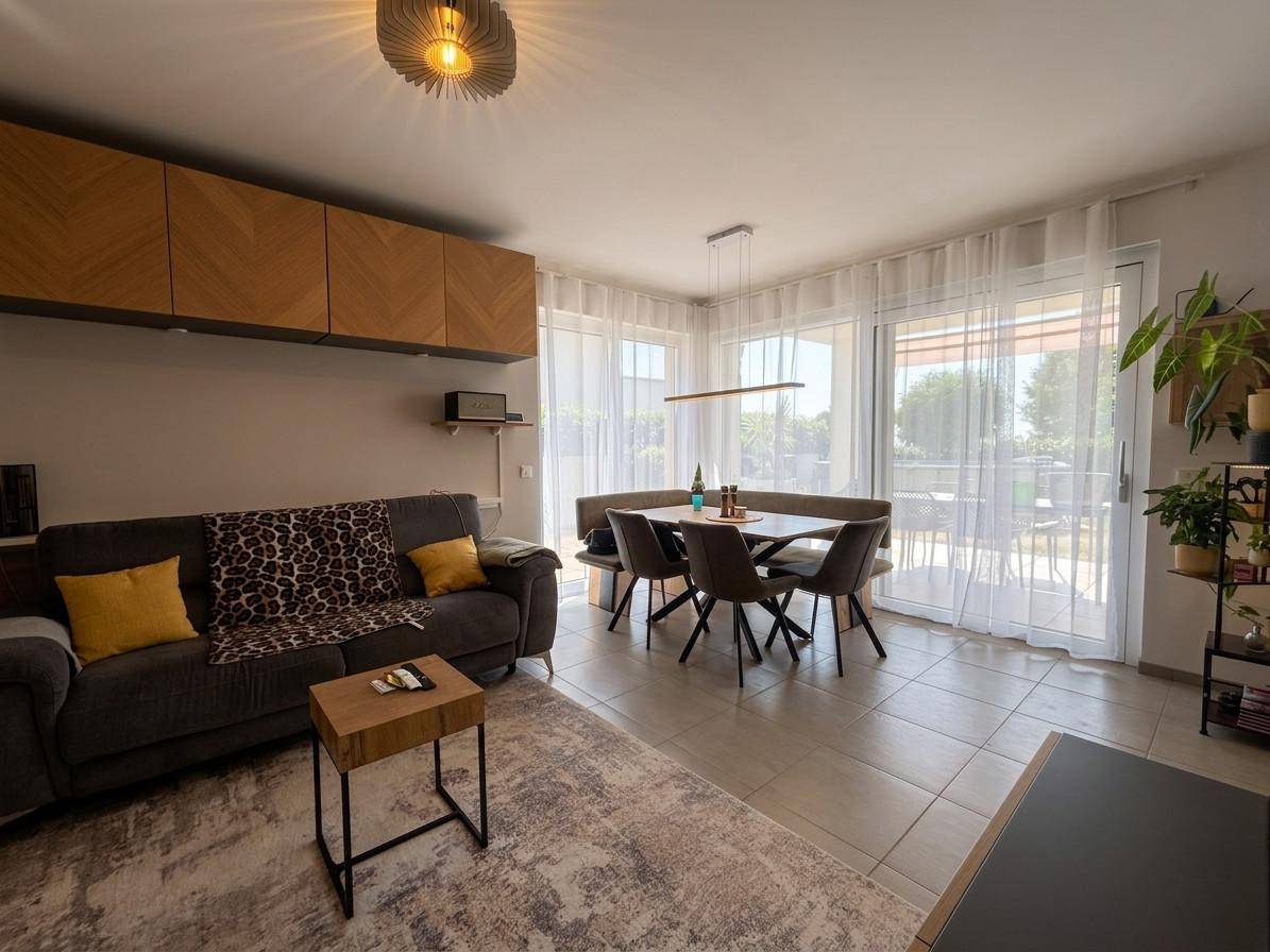 Lichtdurchfluteter Wohn-Essbereich mit Zugang zur Terrasse und modernen Möbeln in warmen Tönen.