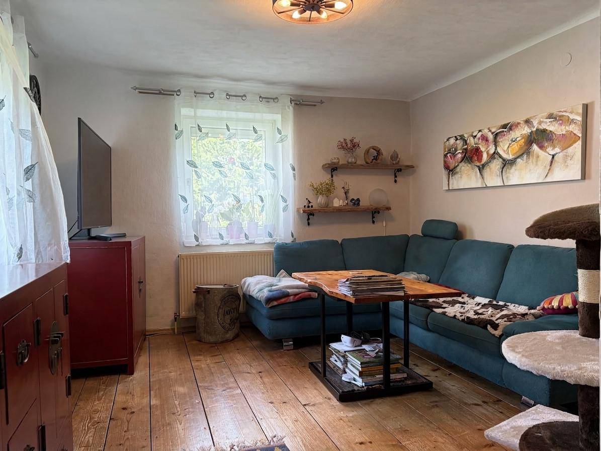 Gemütliches Wohnzimmer mit Holzboden, tealfarbenem Sofa und rustikalen Dekorationselementen.