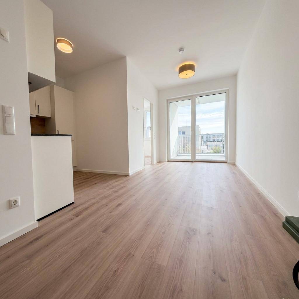 Lichtdurchfluteter Wohnbereich mit Zugang zu einem Balkon oder einer Terrasse und modernem Laminatboden.