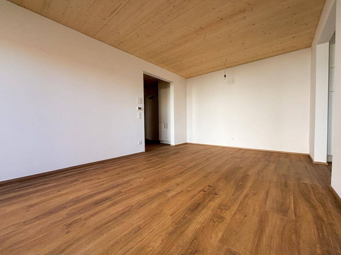 Geräumiger, unmöblierter Wohnbereich mit Holzboden und Holzdecke, bereit zum Einzug.