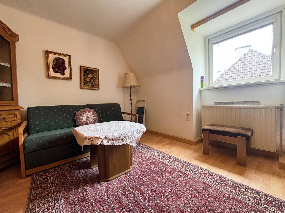 Wohnzimmer mit Sofa, Couchtisch und Fenster, das viel Tageslicht hereinlässt.