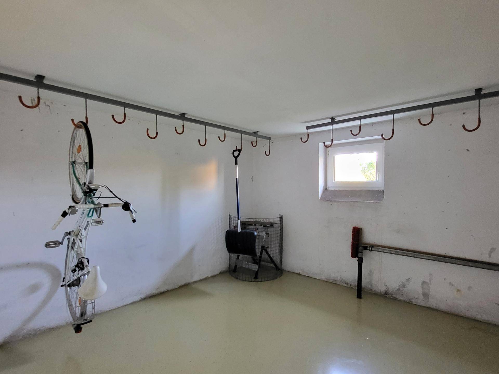 Fahrradraum im Keller mit praktischen Aufhängemöglichkeiten und einem kleinen Fenster für Belüftung.