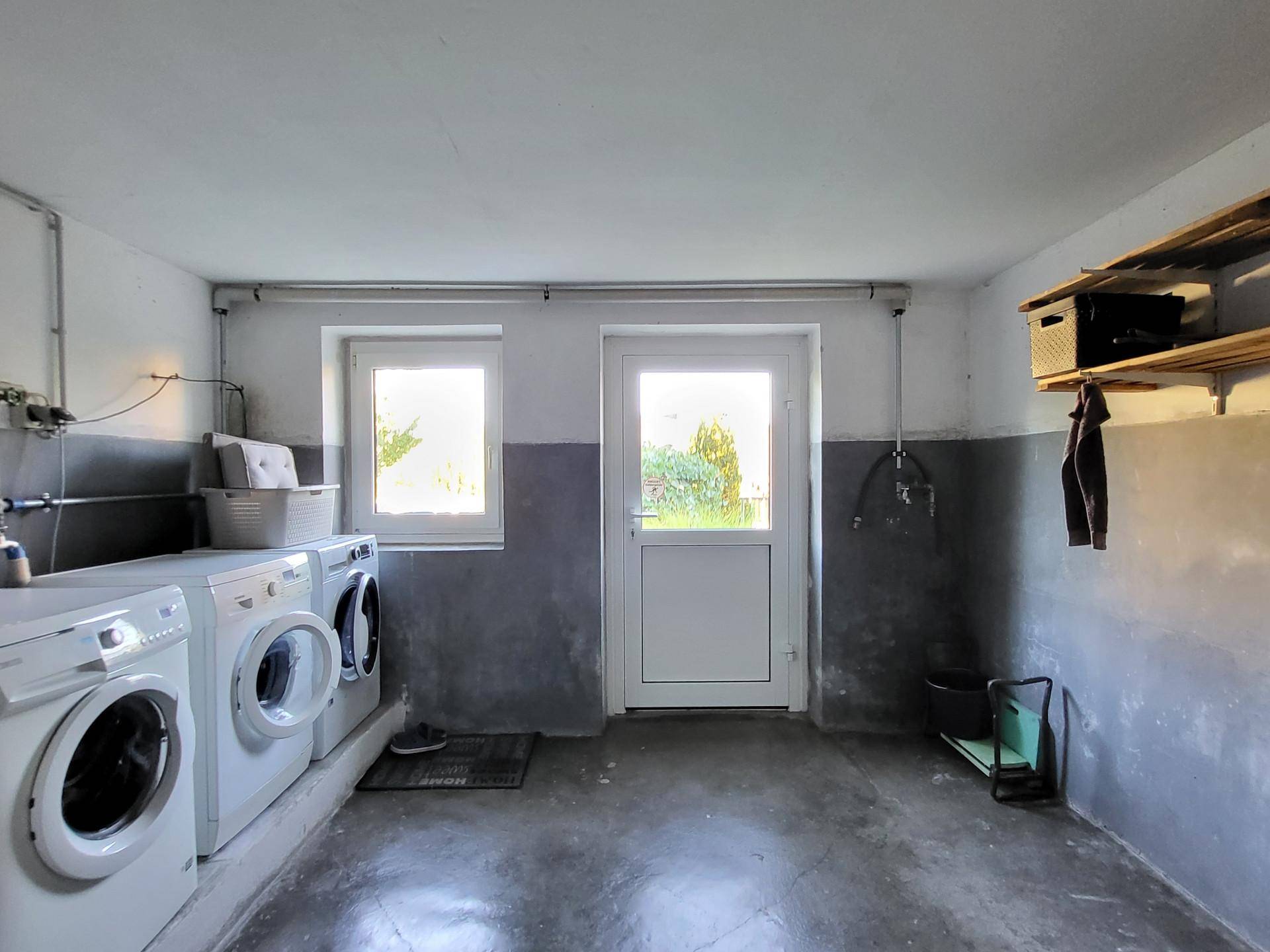 Funktionaler Waschraum im Keller mit Waschmaschinen und Zugang zum Garten, praktisch und geräumig.