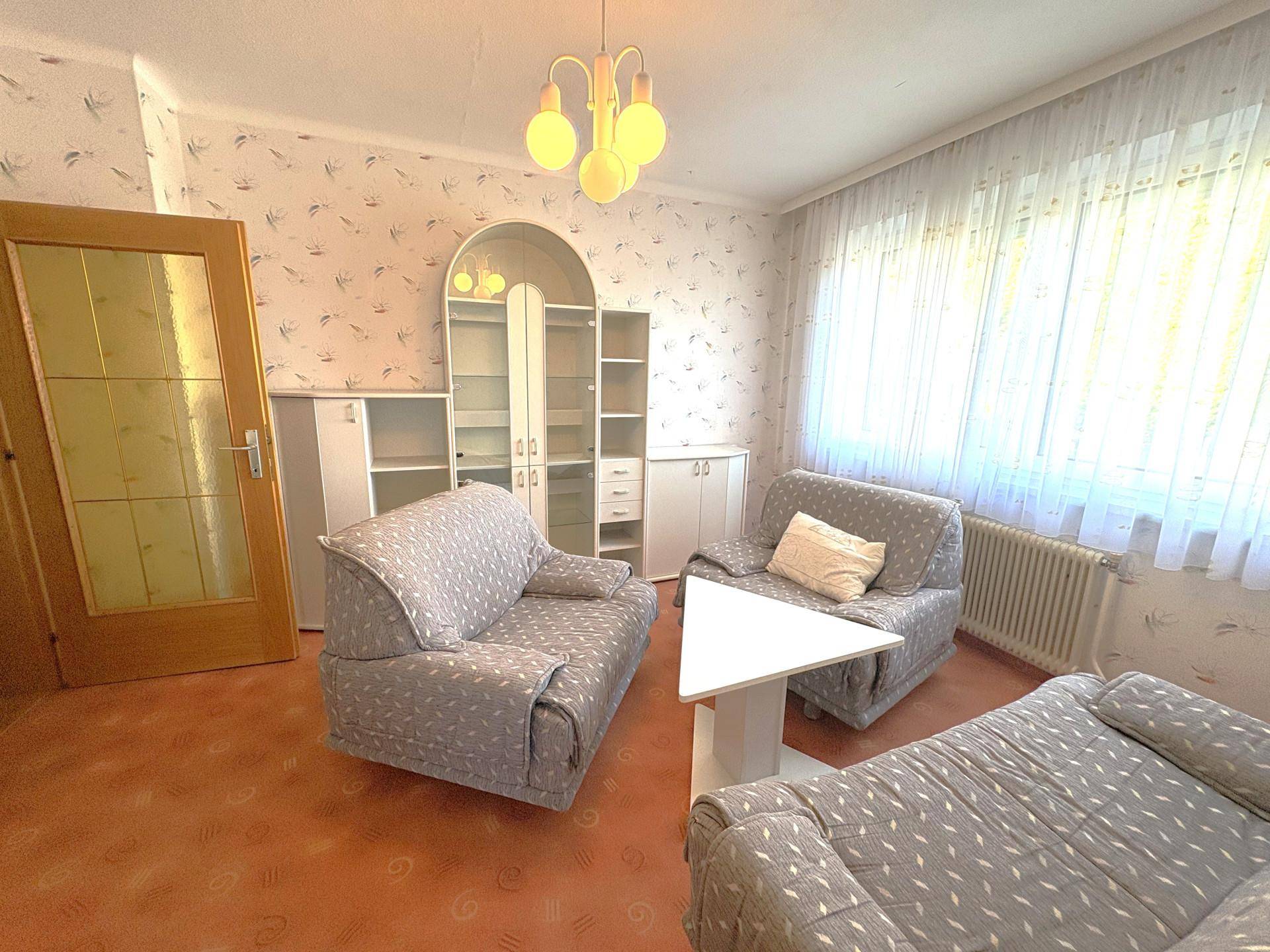 Gemütliches Wohnzimmer mit gemusterter Tapete, bequemen Sofas und einem Couchtisch.