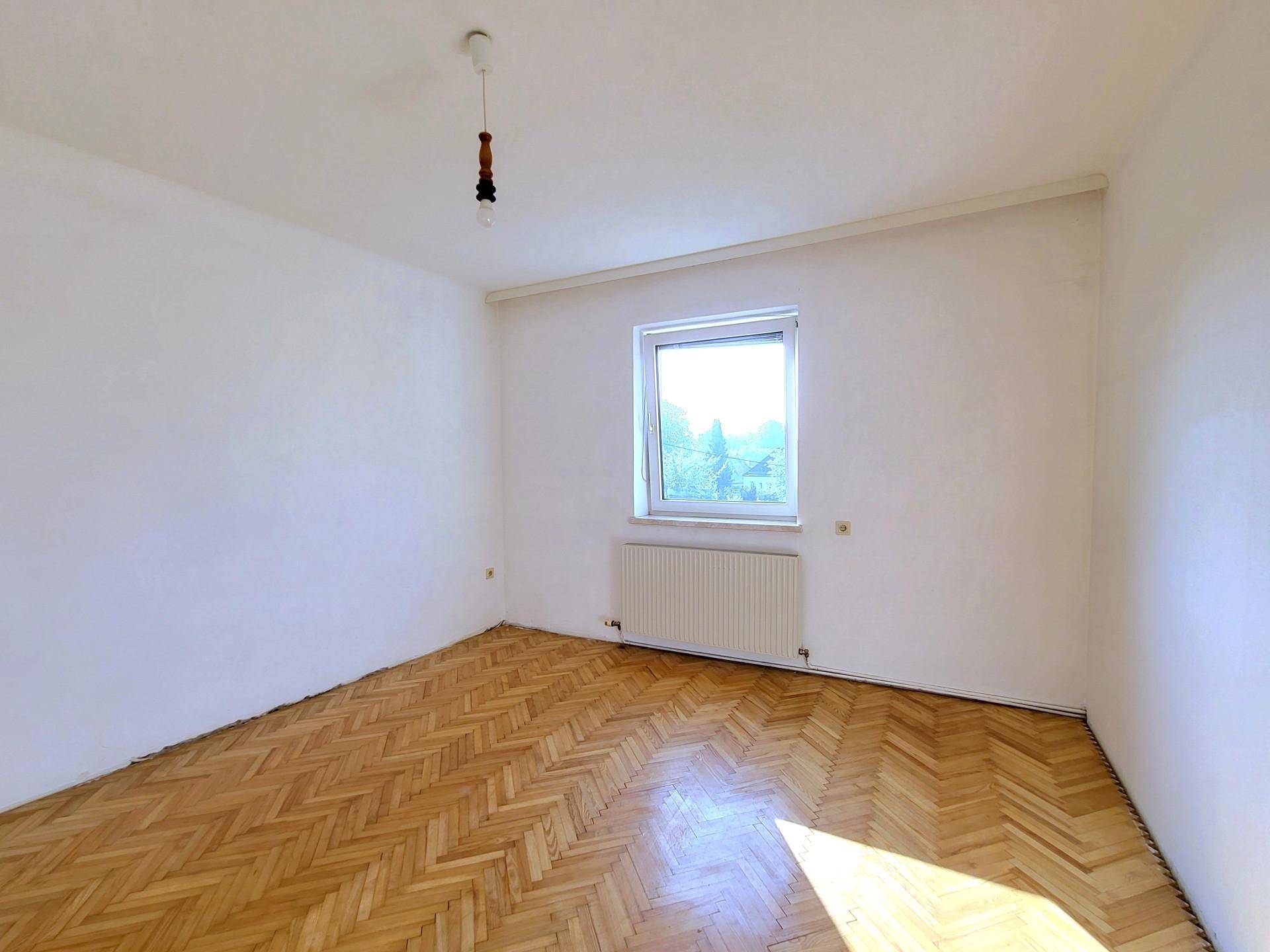 Schlafzimmer mit Fischgrätparkett, einem Fenster und viel natürlichem Lichteinfall für eine angenehme Atmosphäre.