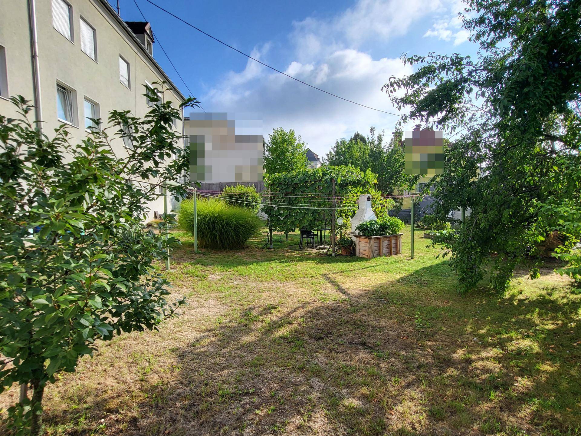 Weitläufiger Gartenbereich mit Rasenfläche und Bäumen im Hintergrund, bietet viel Platz im Freien.
