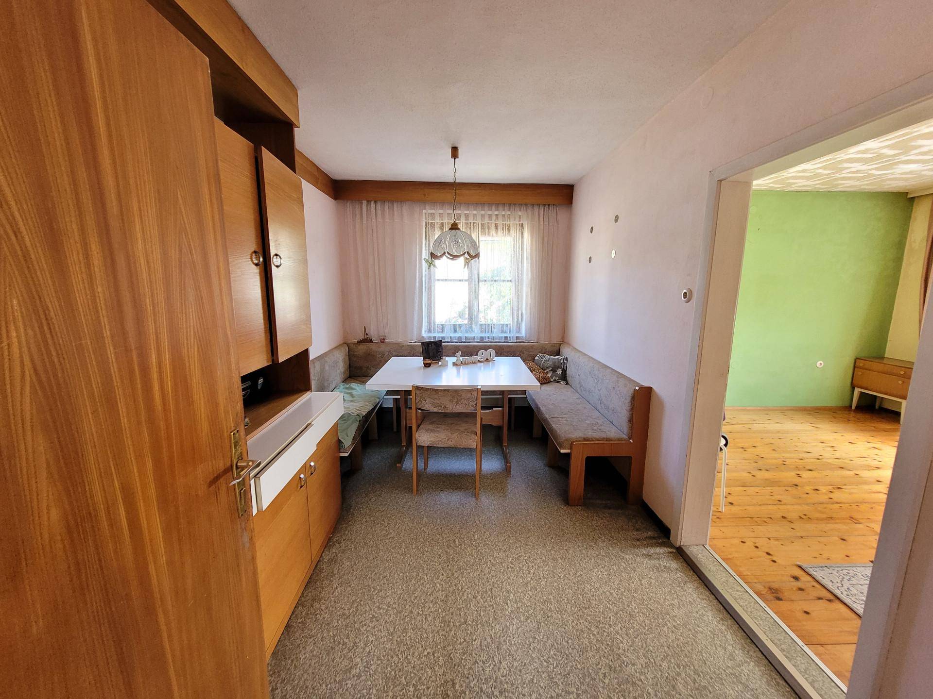 Essbereich mit Eckbank, Teppichboden und Blick in einen angrenzenden Raum.