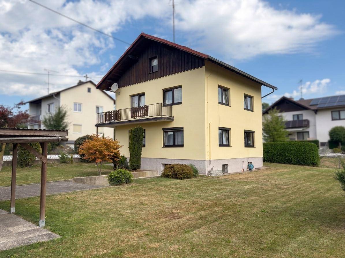 Freistehendes Haus mit Balkon und großem Gartenbereich, umgeben von weiterer Wohnbebauung.