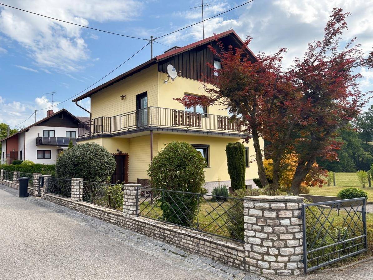 Ansicht des Hauses von der Straße mit dekorativem Zaun und üppiger Bepflanzung.
