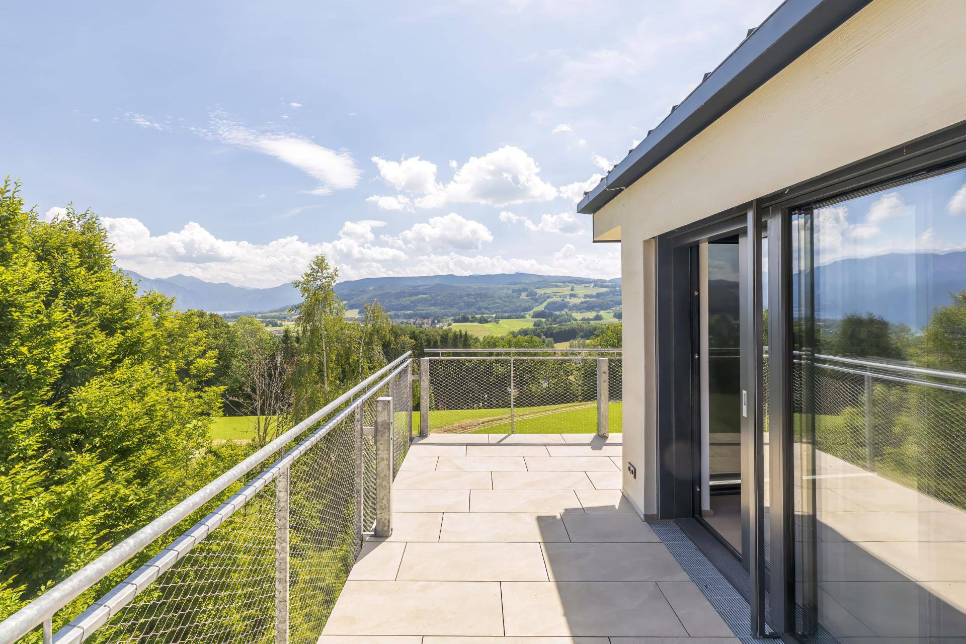Geräumiger Balkon mit moderner Metallbrüstung und weitem Blick über die grüne Landschaft.