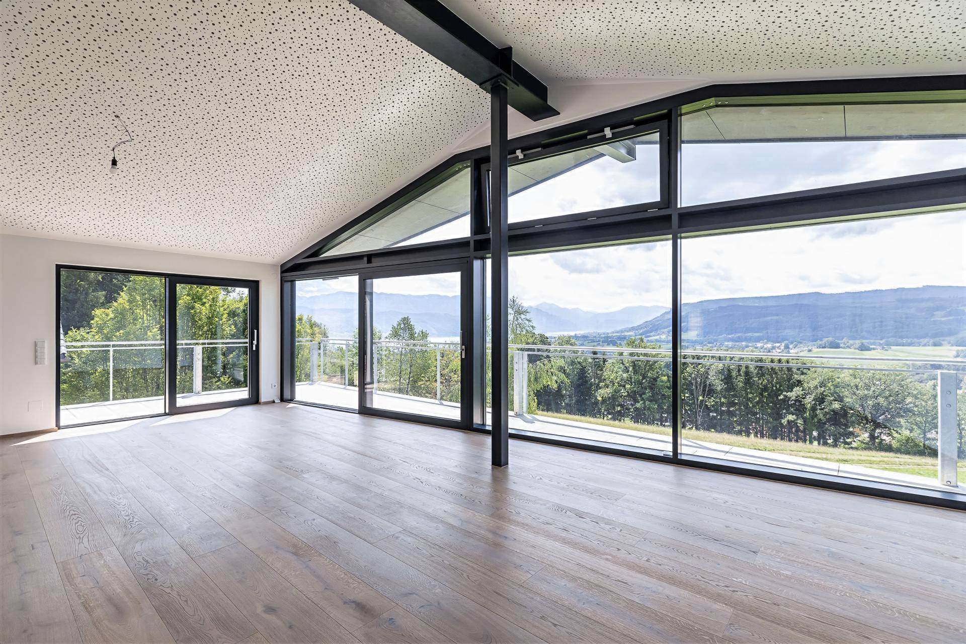 Heller, leerer Raum mit hohen Decken und raumhohen Fenstern, die einen beeindruckenden Panoramablick bieten.