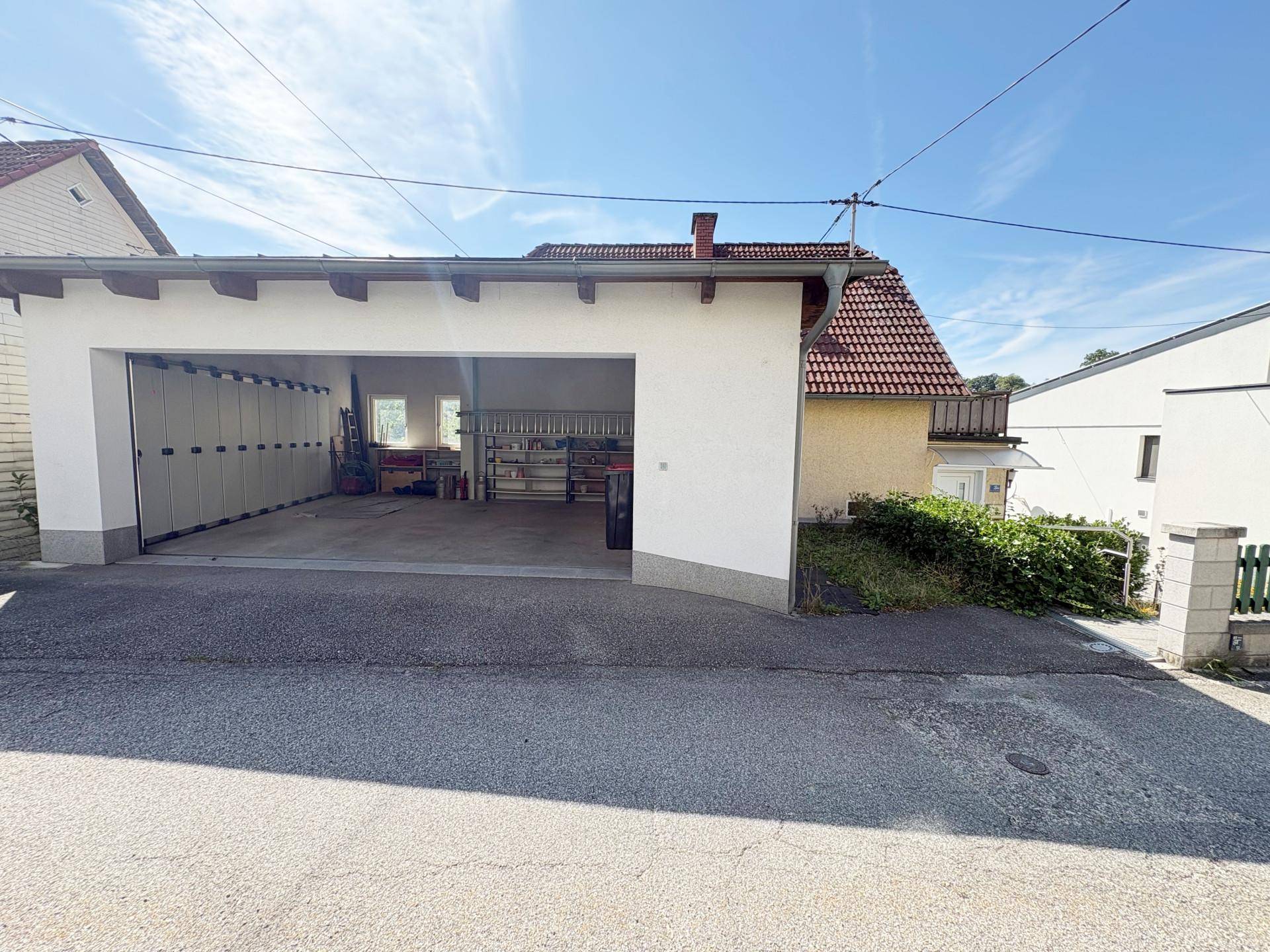 Geräumige Doppelgarage mit offenem Tor und Zufahrt neben dem Wohnhaus.