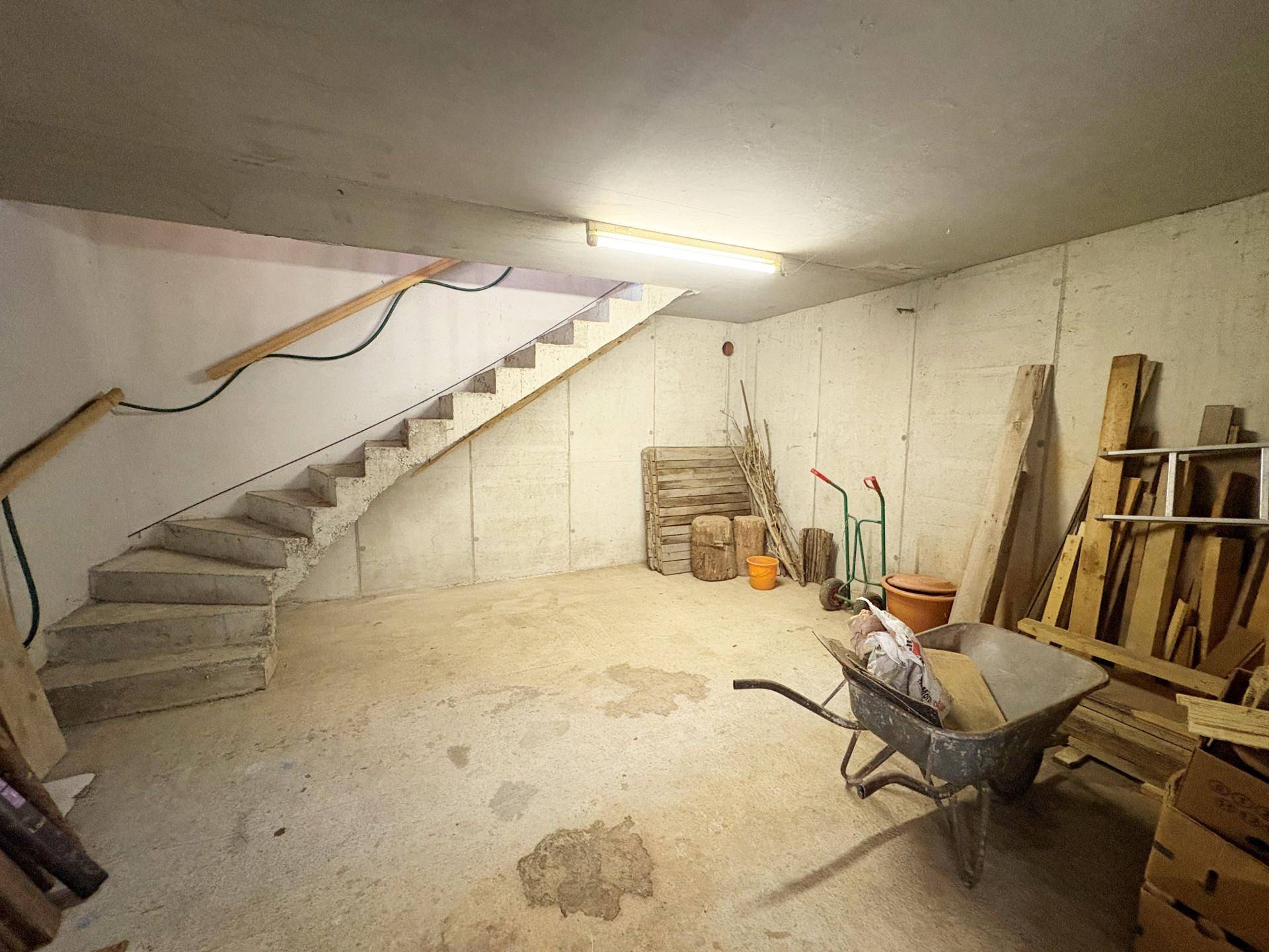 Unausgebauter Kellerraum mit Betontreppe und viel Stauraum für Werkzeuge und Material.