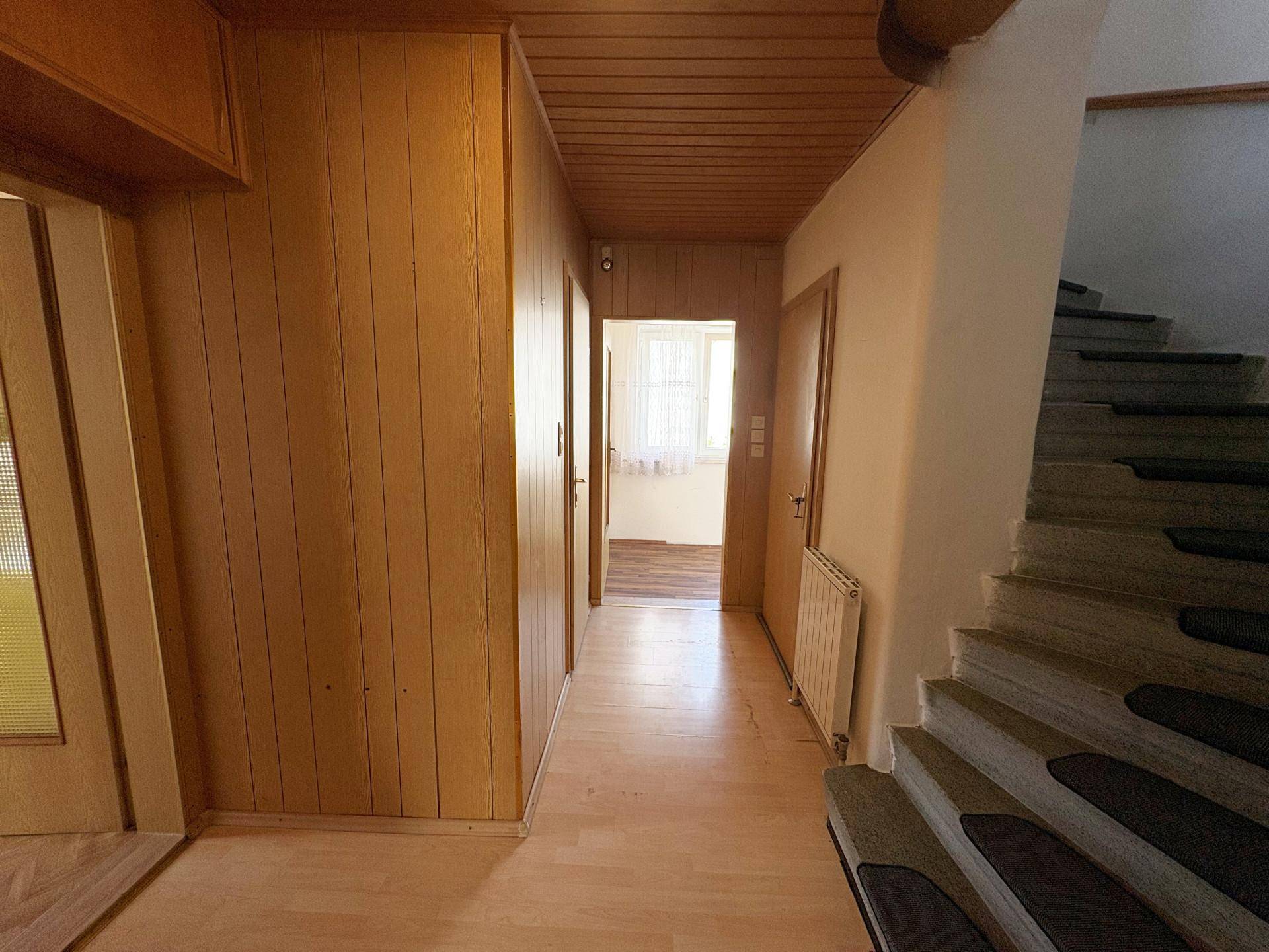Flur mit Holzvertäfelung, Treppe und Zugang zu weiteren Räumen.