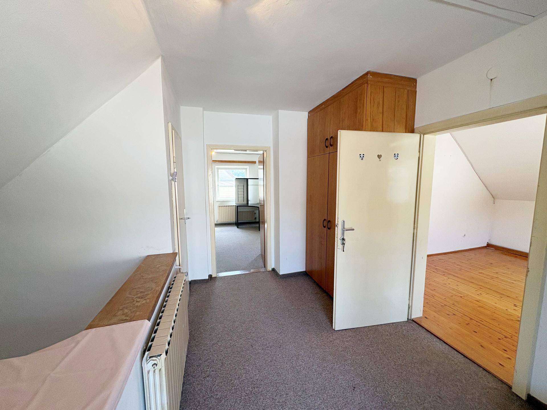 Dachgeschossflur mit Teppichboden, Einbauschrank und Zugang zu den Zimmern.