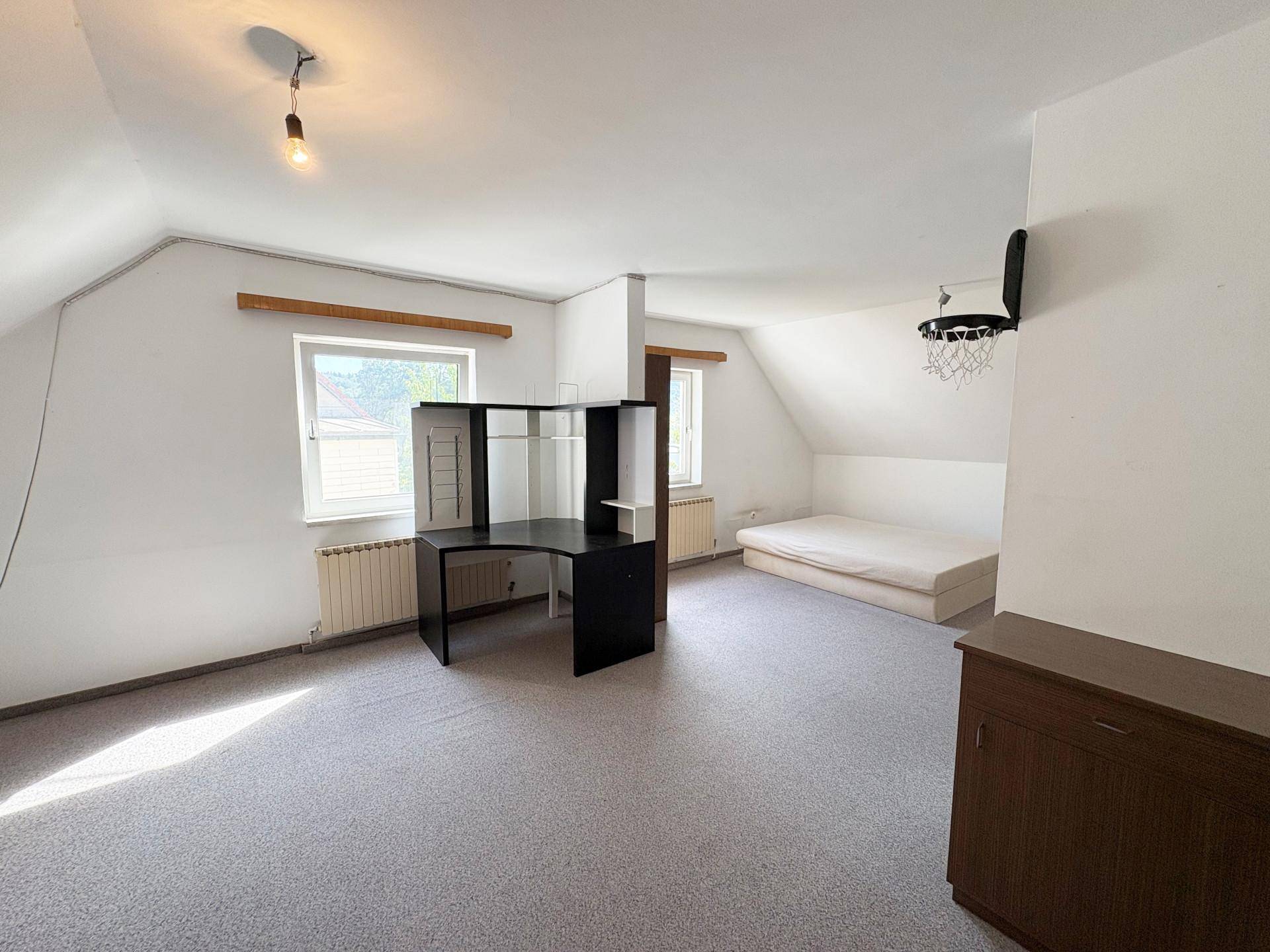 Geräumiges Dachzimmer mit Schreibtisch, Bett und Teppichboden, ideal als Jugendzimmer.