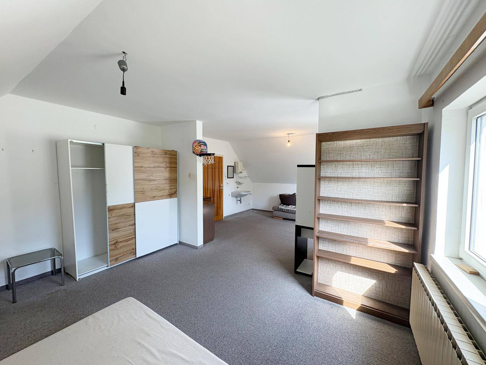 Großes Dachzimmer mit Teppichboden, Kleiderschrank und integriertem Waschbecken.