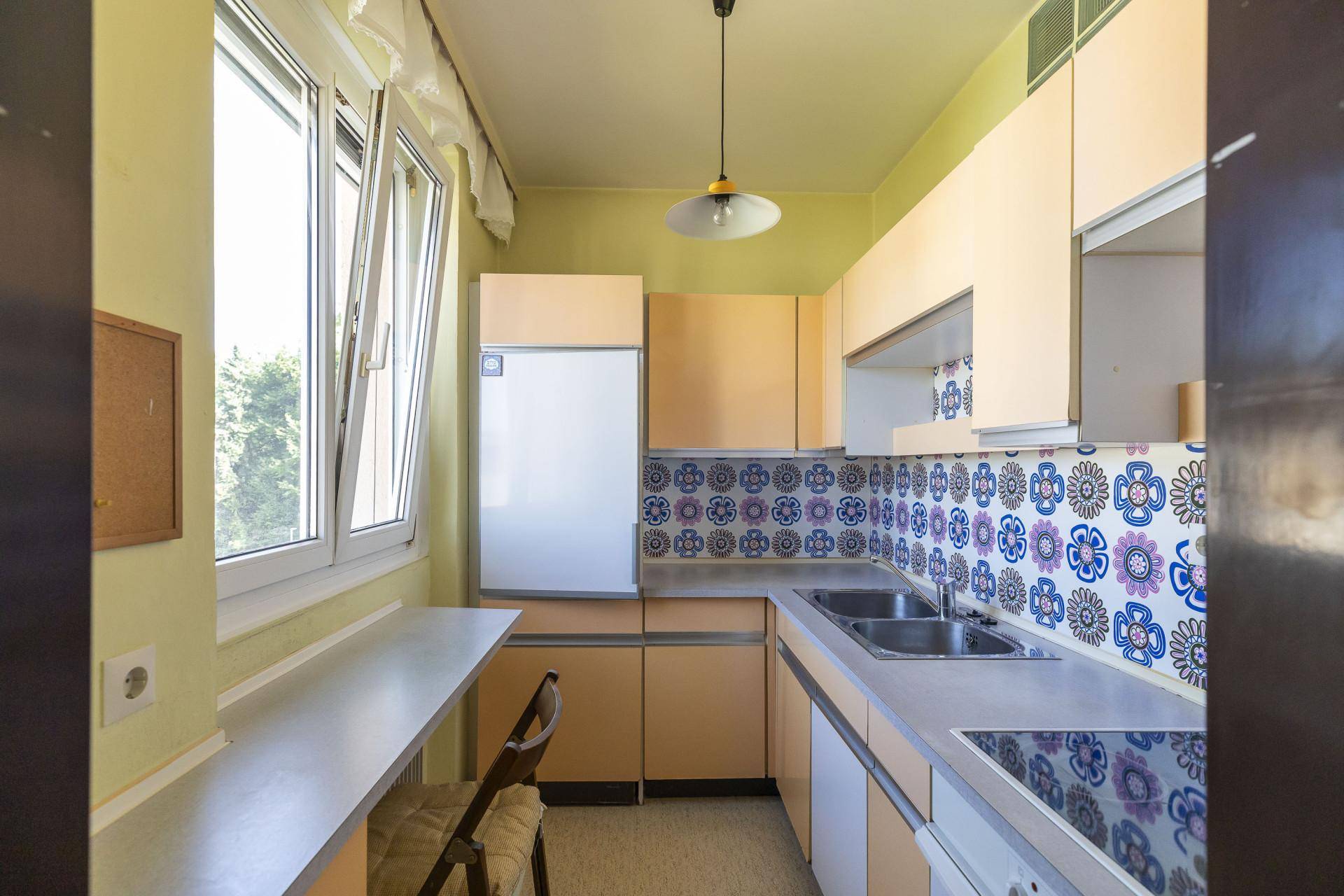 Funktionale Küche im Retro-Stil mit gemusterten Fliesen und Fensterblick ins Grüne.