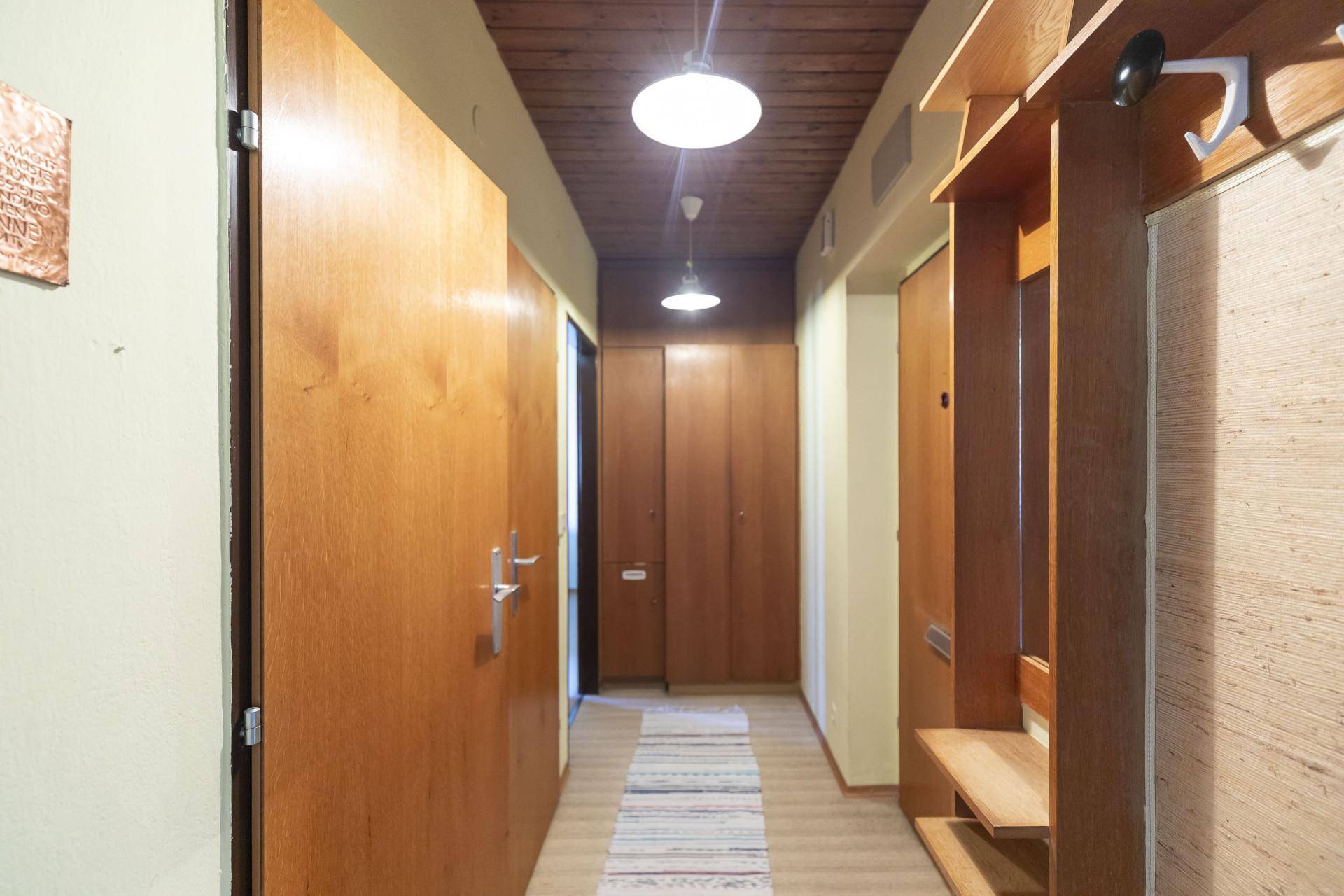 Langer Flur mit Holzvertäfelung, Garderobe und Zugang zu verschiedenen Räumen.