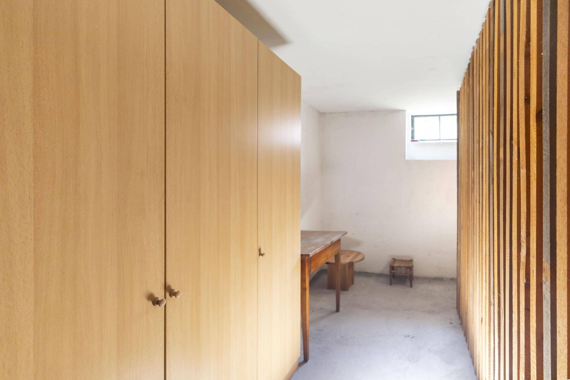 Kellerraum mit Holzverkleidung, kleinem Fenster und Stauraum.