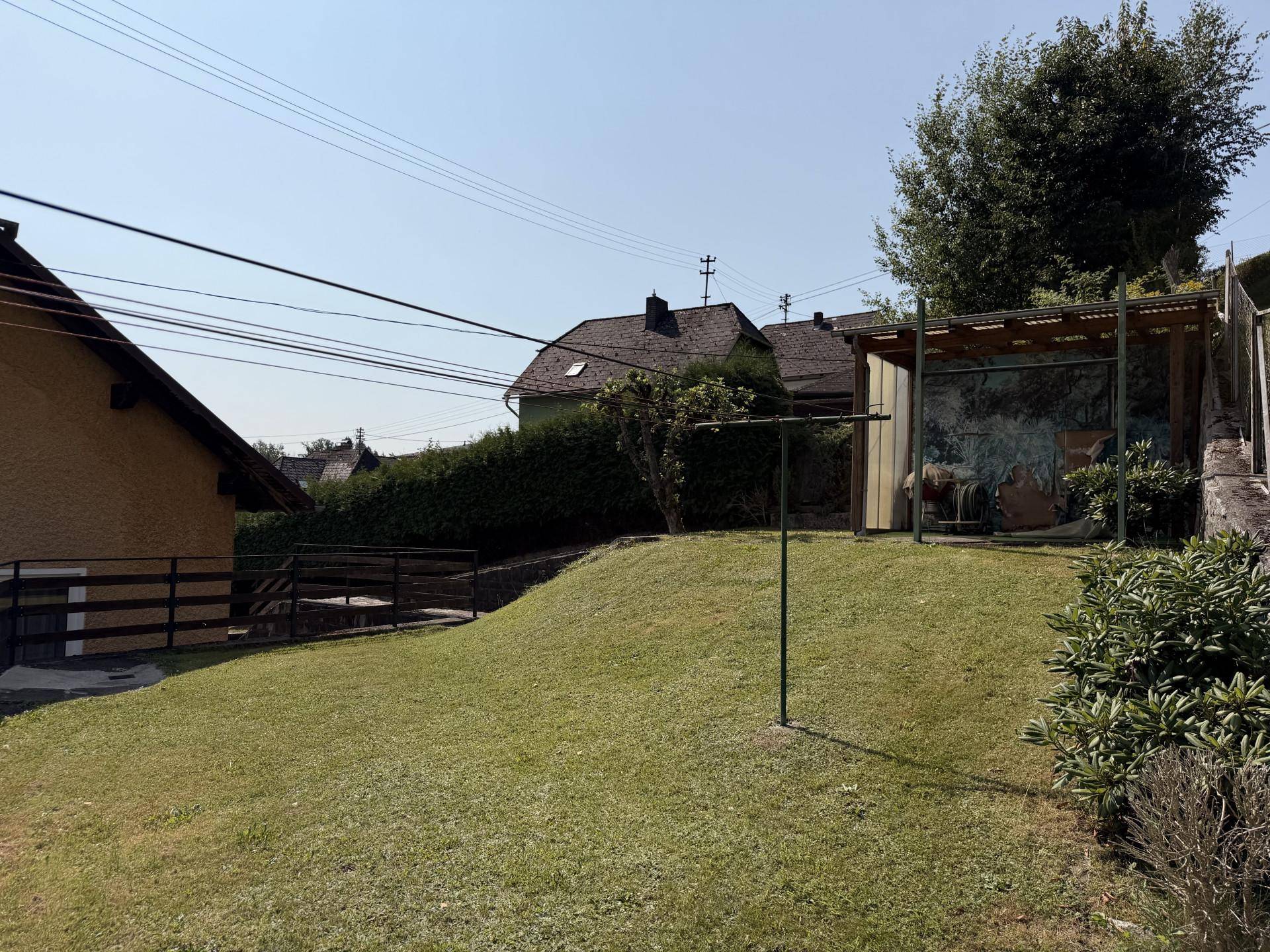 Garten mit Rasenfläche, Wäscheleine und einem kleinen Unterstand, ideal für den Außenbereich.
