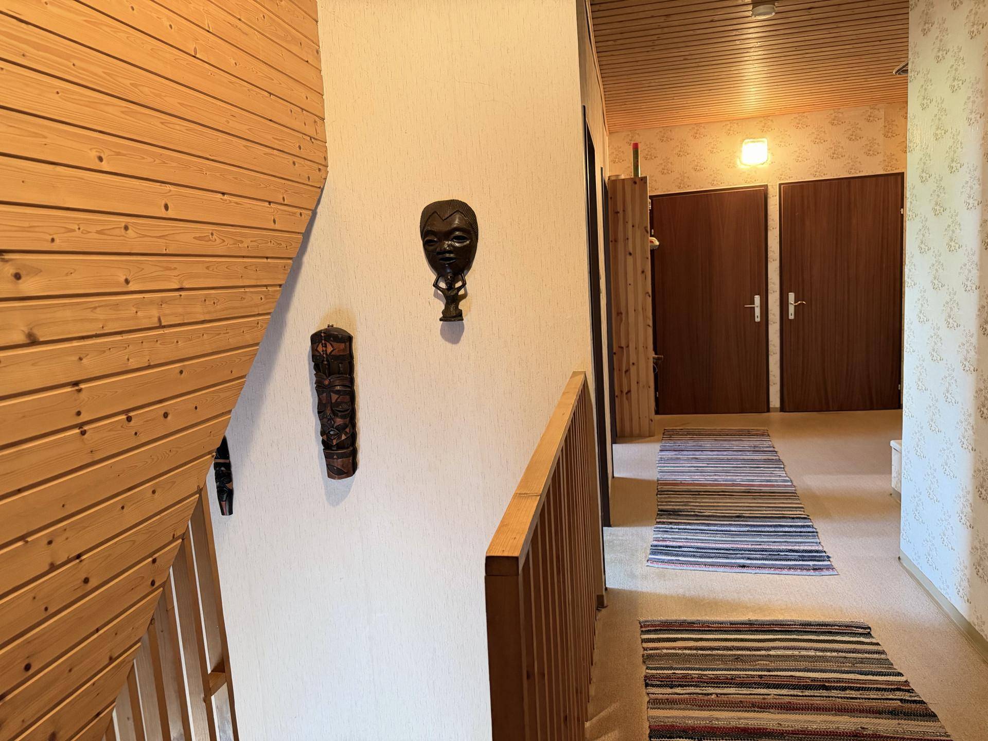 Treppenhaus und Flur im Obergeschoss mit Holzverkleidung und traditioneller Dekoration.