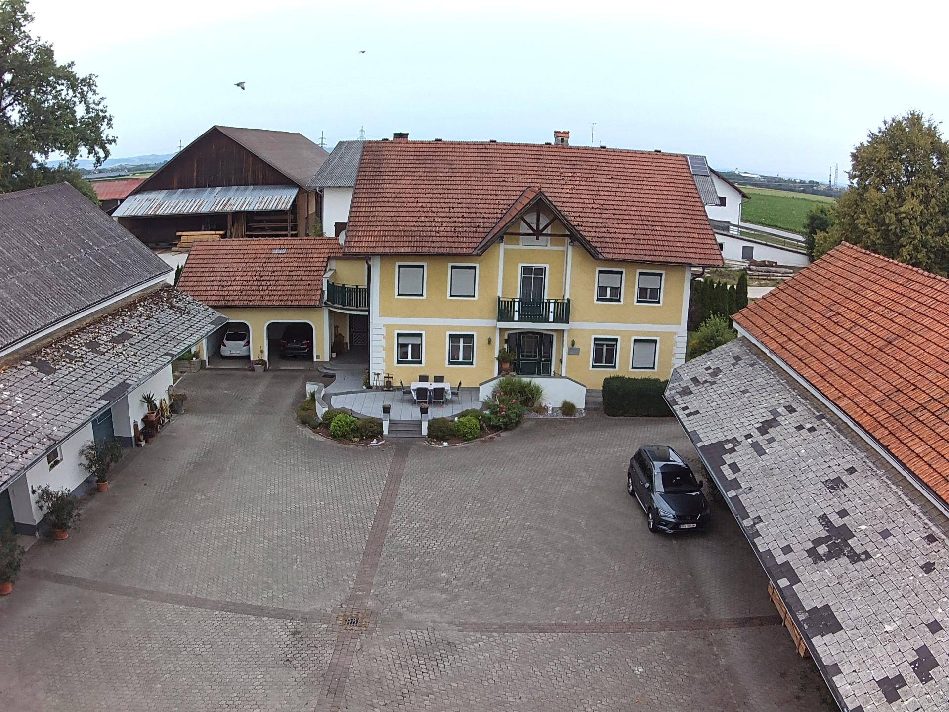 Weitläufiger Hofbereich mit dem Haupthaus und weiteren Gebäuden, umgeben von ländlicher Idylle.