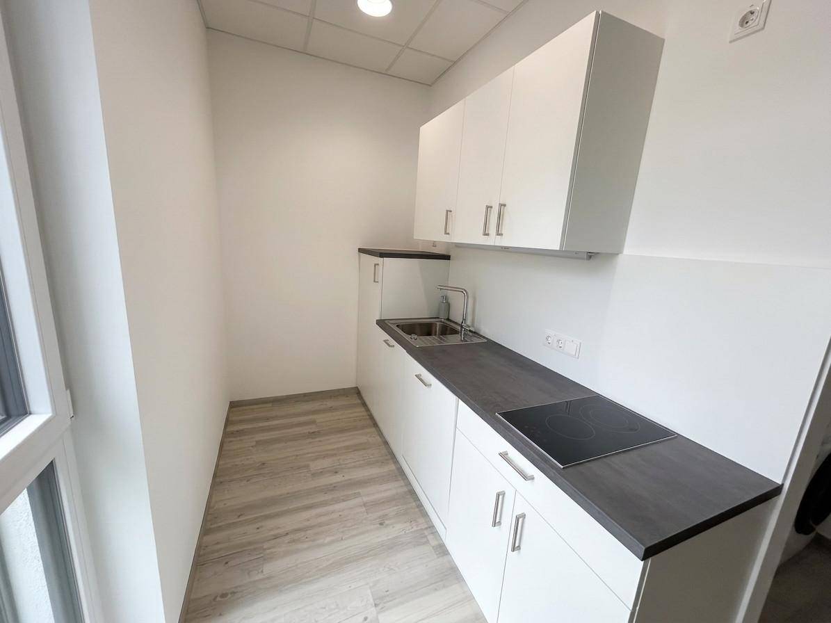 Moderne Küchenzeile mit weißen Schränken, dunkler Arbeitsplatte und Induktionskochfeld.