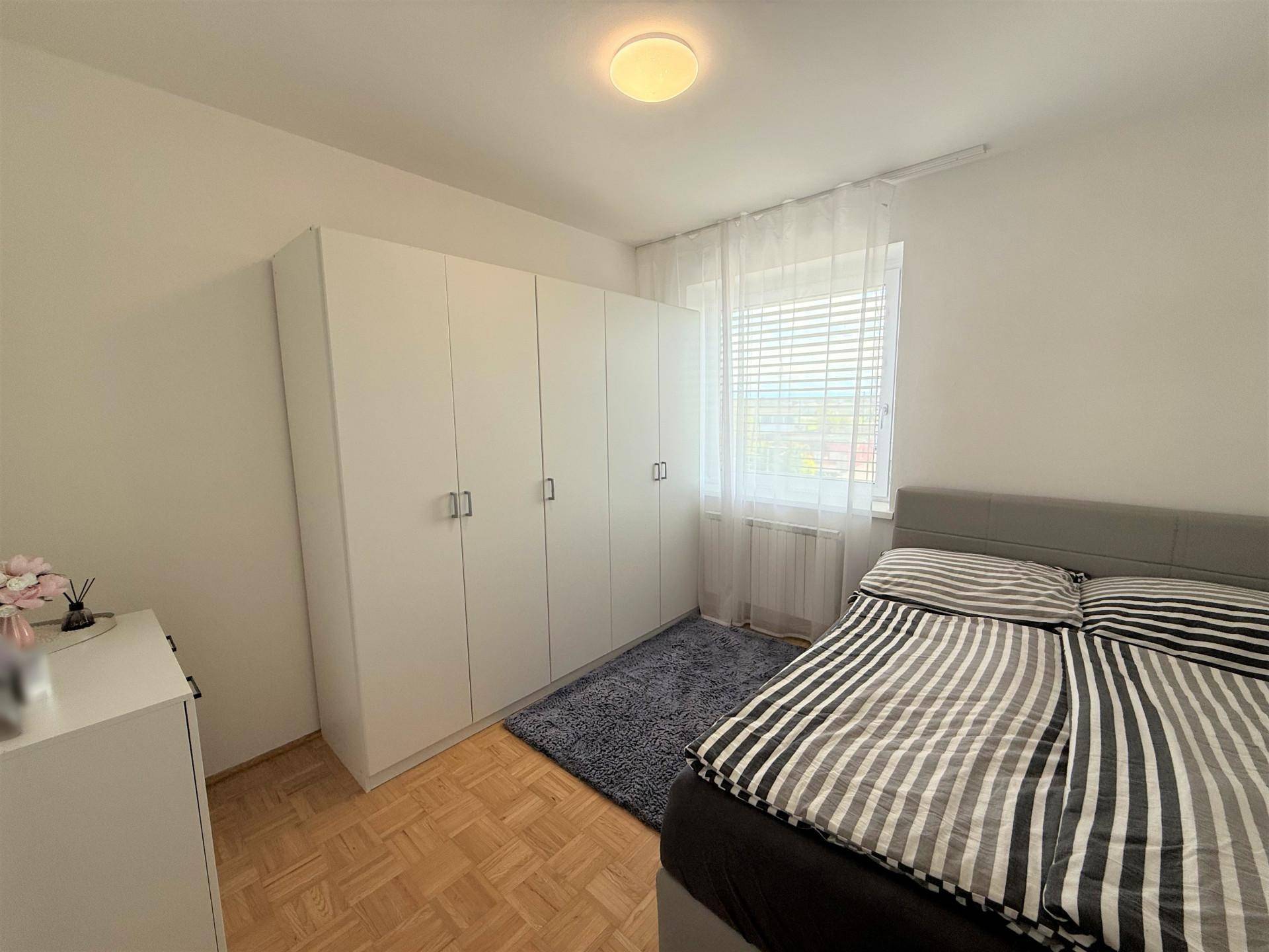 Schlafzimmer mit großem Bett, weißen Kleiderschränken und Parkettboden, bietet viel Stauraum.